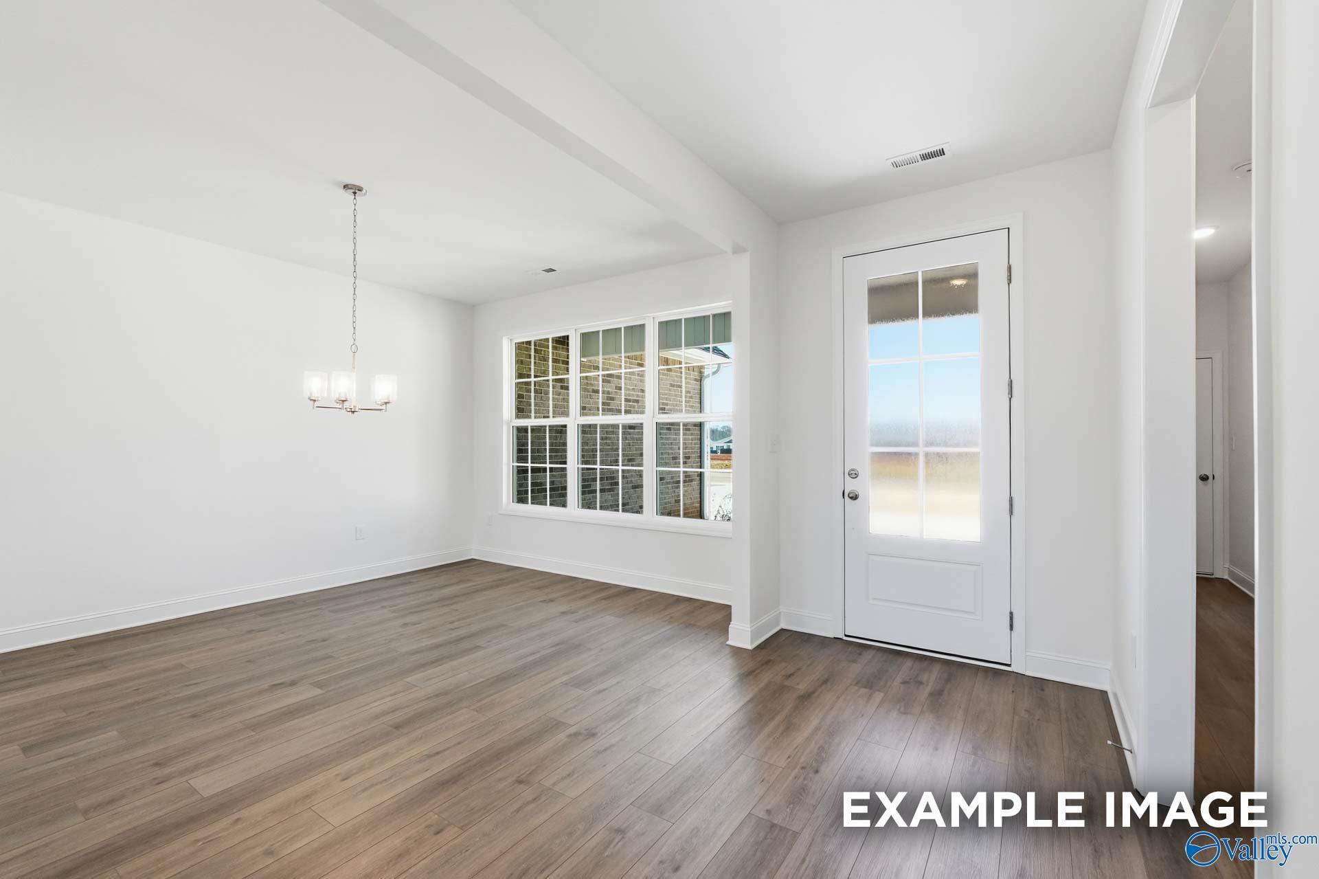Bright dining area with wood-look flooring and glass door in The Valencia floor plan, Briercreek, Meridianville, Alabama.