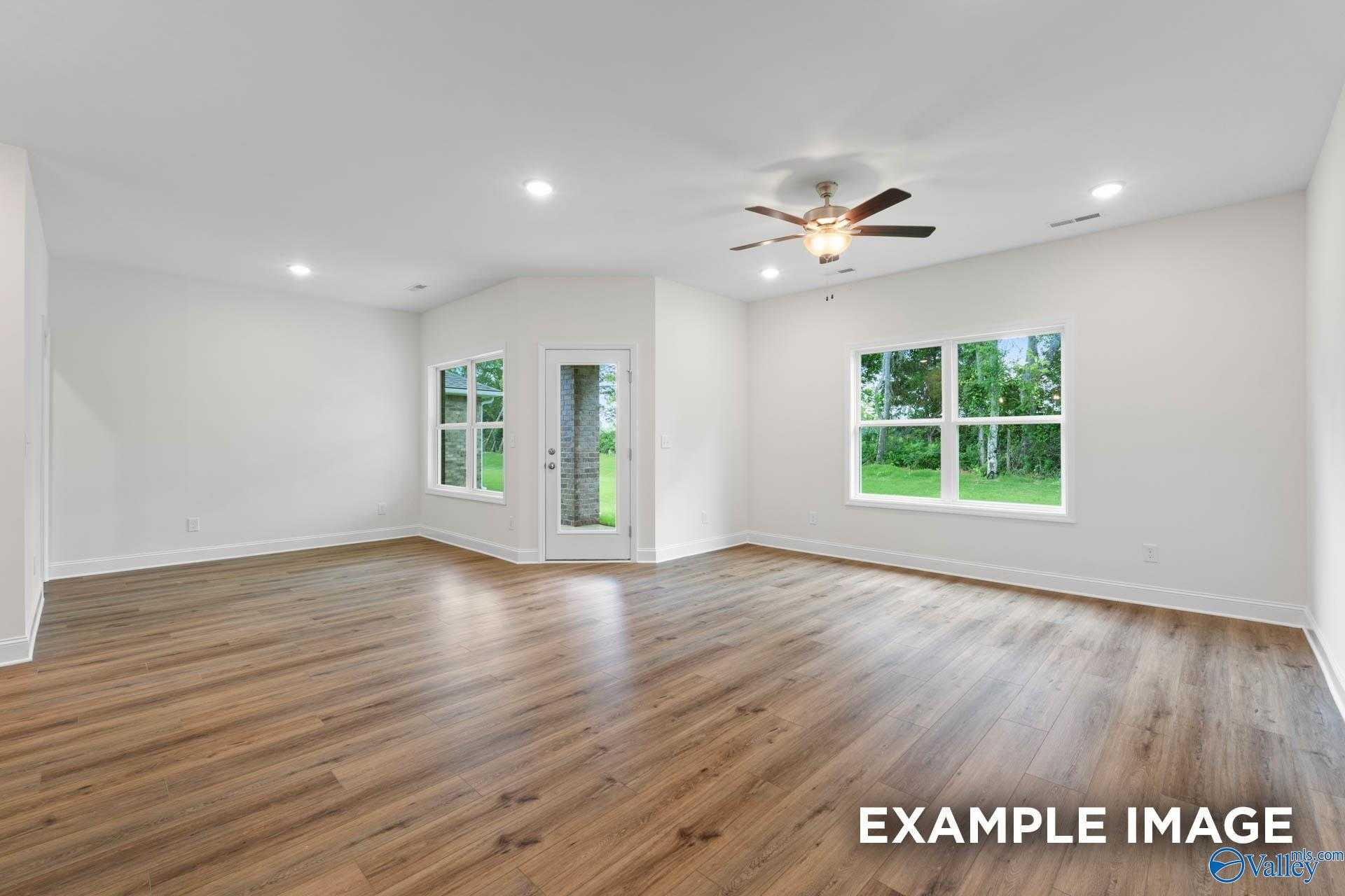 Bright living room with luxury vinyl plank floors, dual ceiling fans, and large windows overlooking backyard in Davidson Homes Daphne D, Athens AL