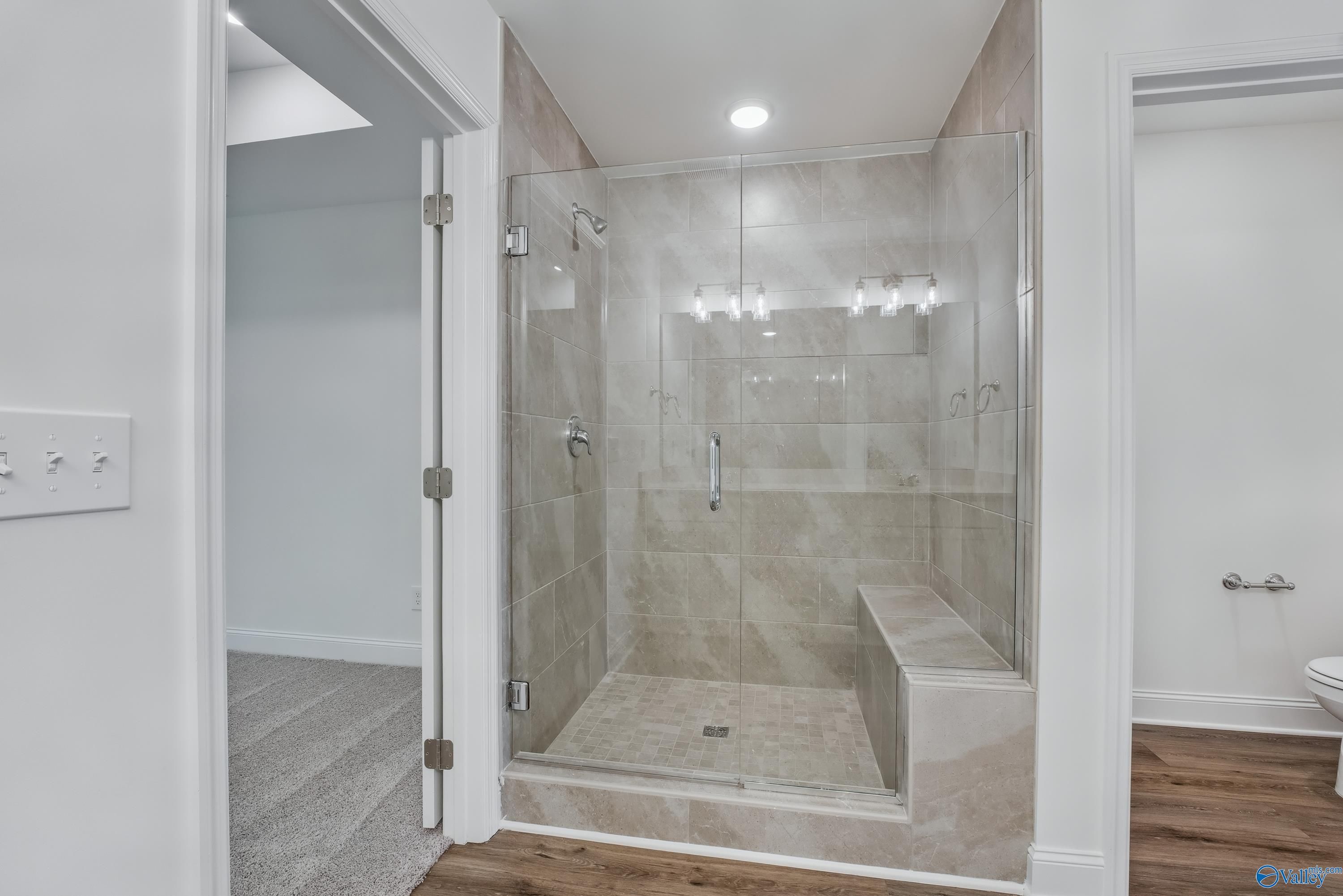 Modern frameless glass shower with tiled bench and vanity in master bath of Davidson Homes Shelby A, Arab, Alabama