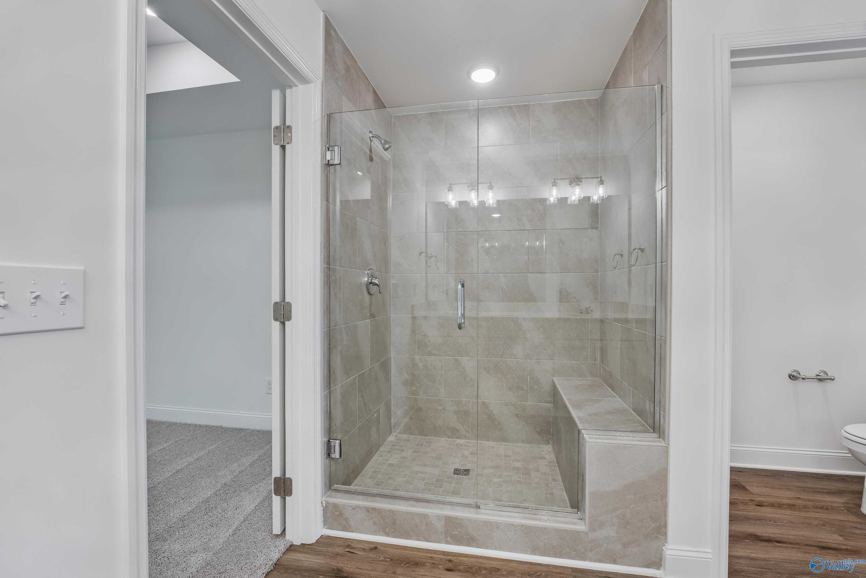Modern frameless glass shower with tiled bench and vanity in master bath of Davidson Homes Shelby A, Arab, Alabama