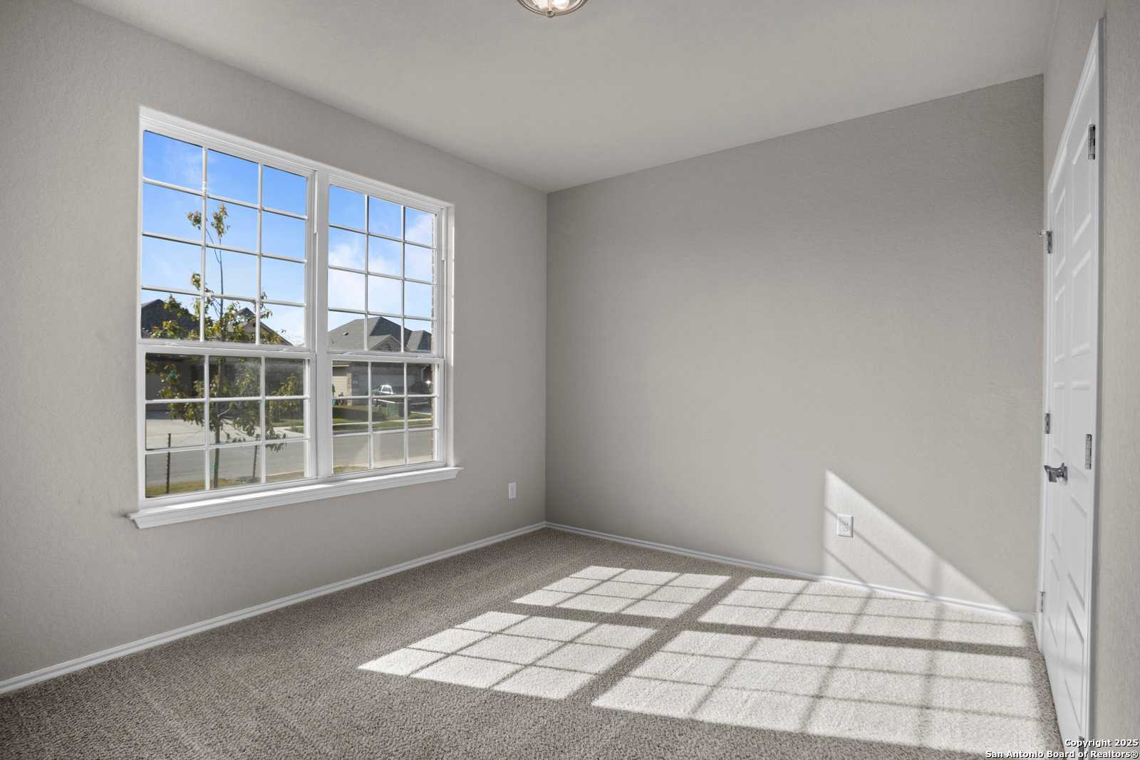Bright bedroom with large window, natural light, and gray walls in The Collin B, Hannah Heights, Seguin, Texas