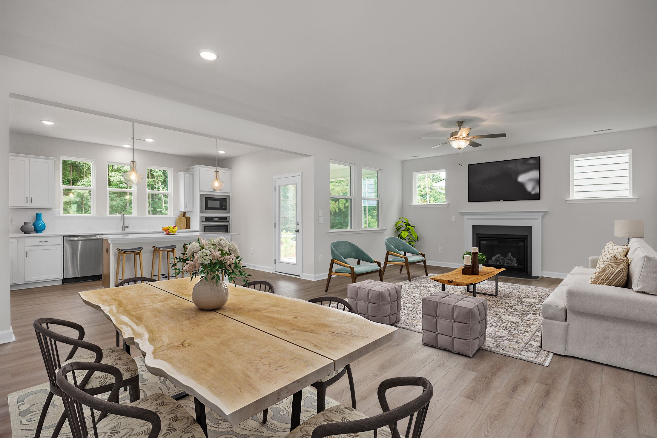 Open-concept kitchen dining living room in Rockport Wake Forest NC by Davidson Homes featuring hardwood floors live-edge table and fireplace