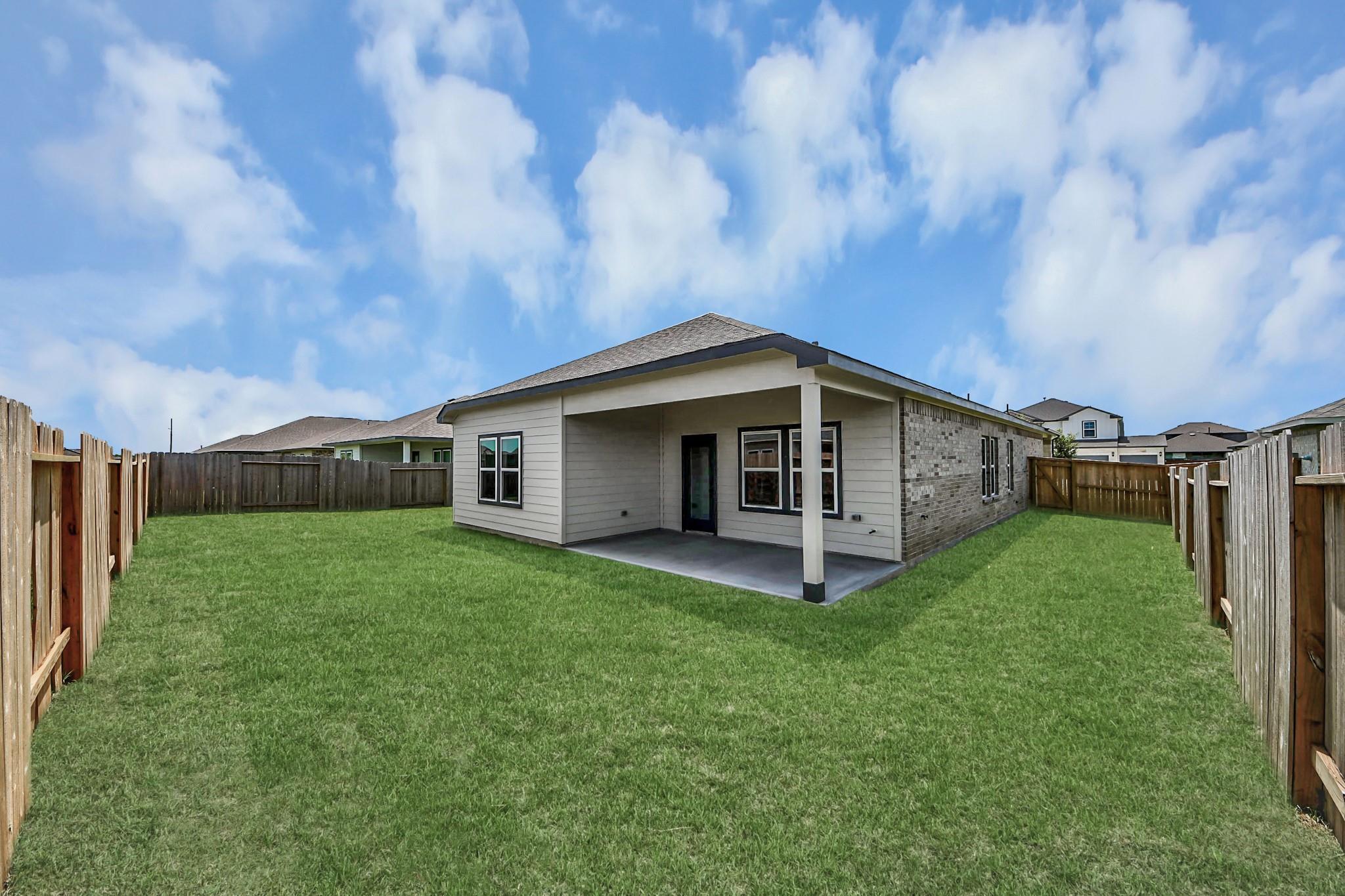 Spacious backyard and covered patio of The Riviera C floor plan home in River Ranch Meadows, Dayton, Texas.