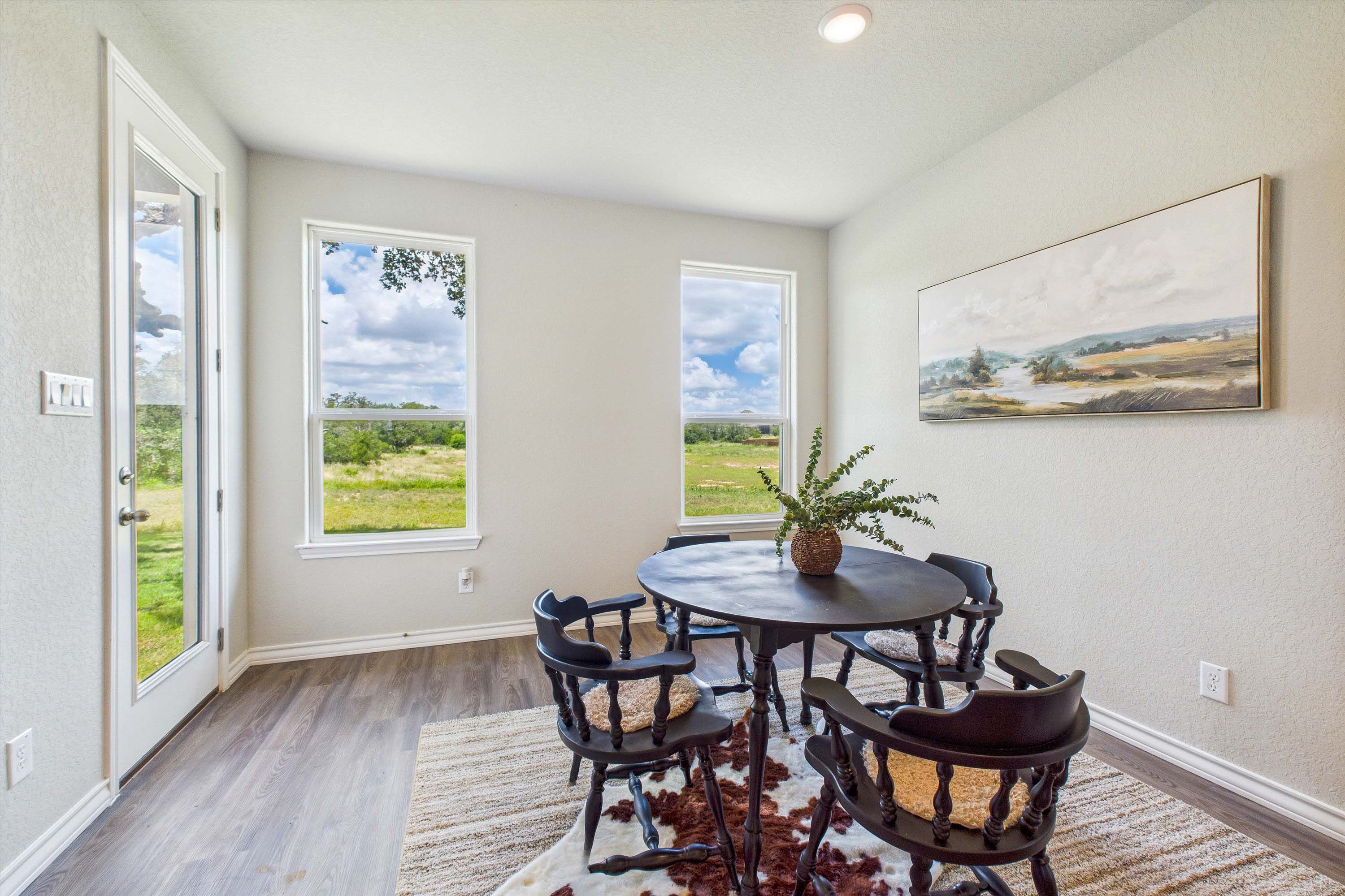 Sunlit breakfast nook in The Foster featuring a round dining table, farmhouse chairs, and scenic views of Castroville, TX.