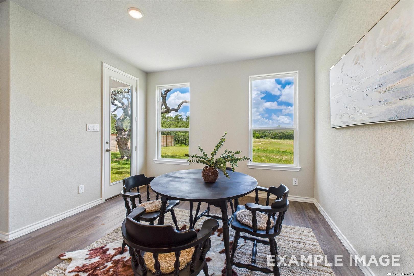 Bright breakfast nook with round table and scenic backyard views in The Foster F floor plan, Potranco Oaks, Castroville.