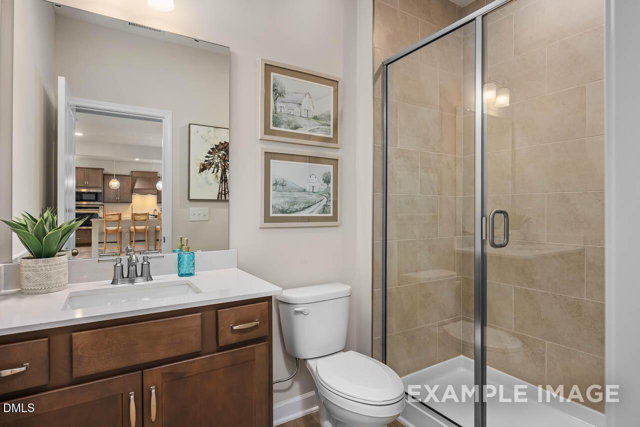 Elegant master bathroom with double vanity, frameless glass shower, and artwork in Davidson Homes The Willow B, Wake Forest