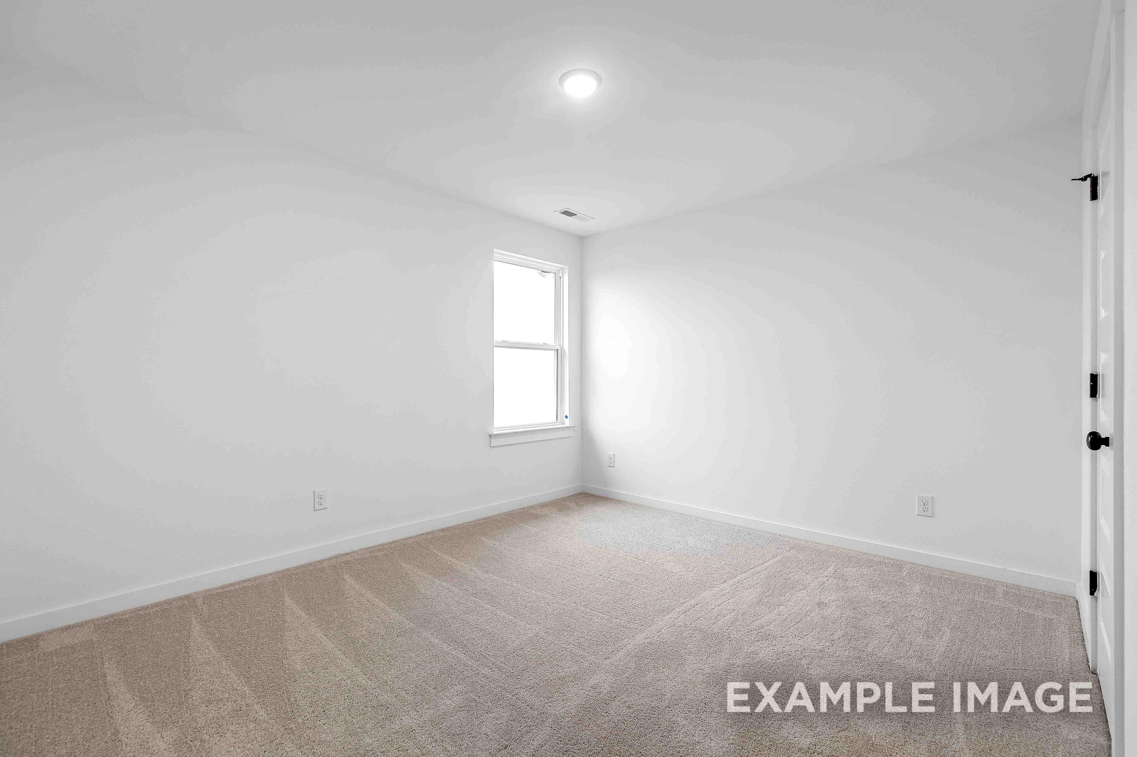 Spacious empty bedroom in The Charleston with white walls, double-hung window, neutral carpet, and closet doors