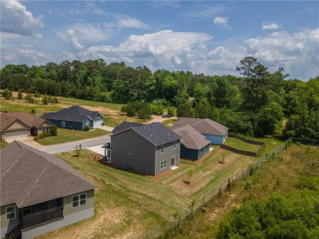 Aerial view of The Bartlett 2-story gray home with 2-car garage amid wooded lots in Summer Vineyard, Phenix City, Alabama