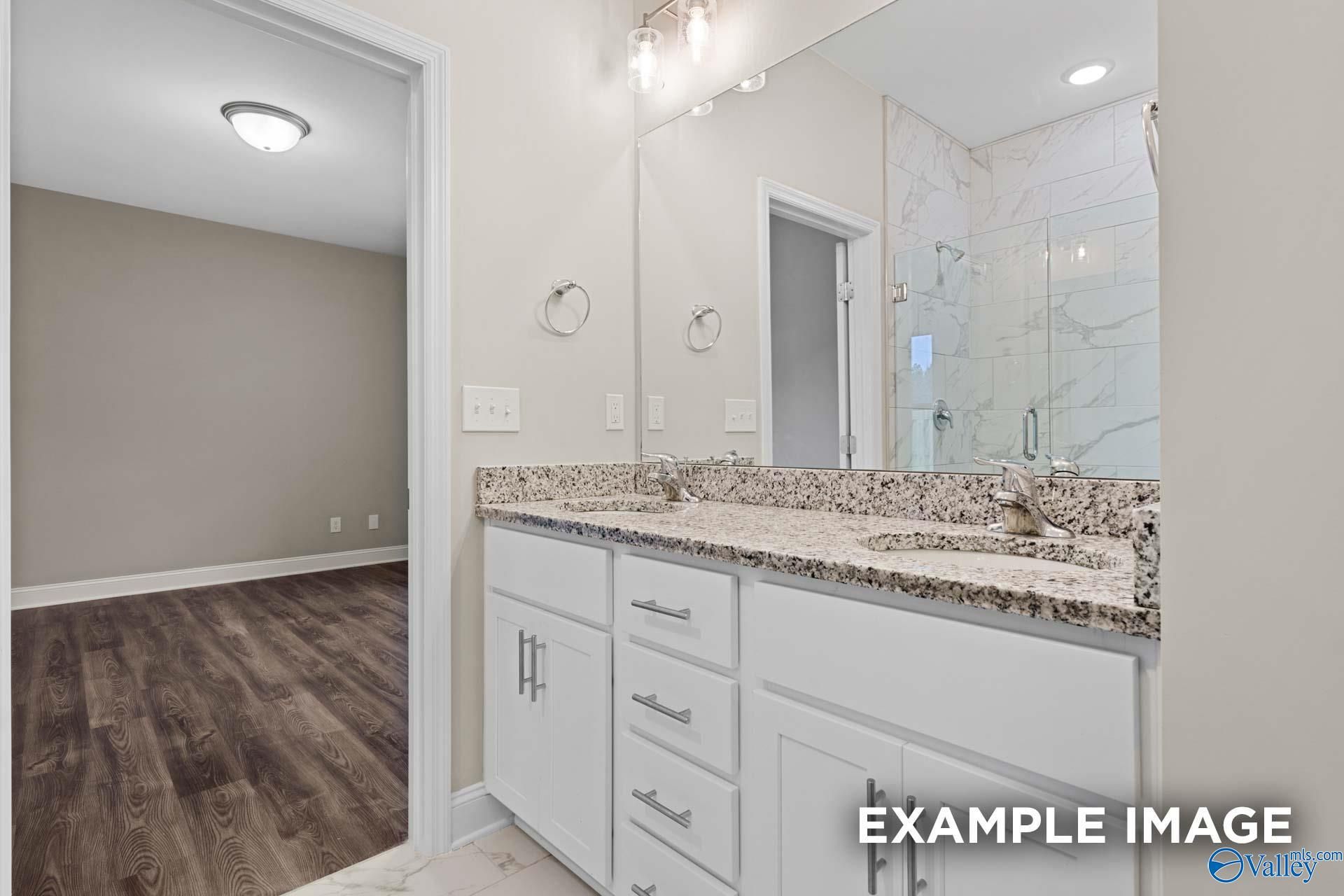 Modern master bathroom featuring double granite vanity, frameless glass shower, and neutral tones in Davidson Homes The Camilla A, Hartselle, AL