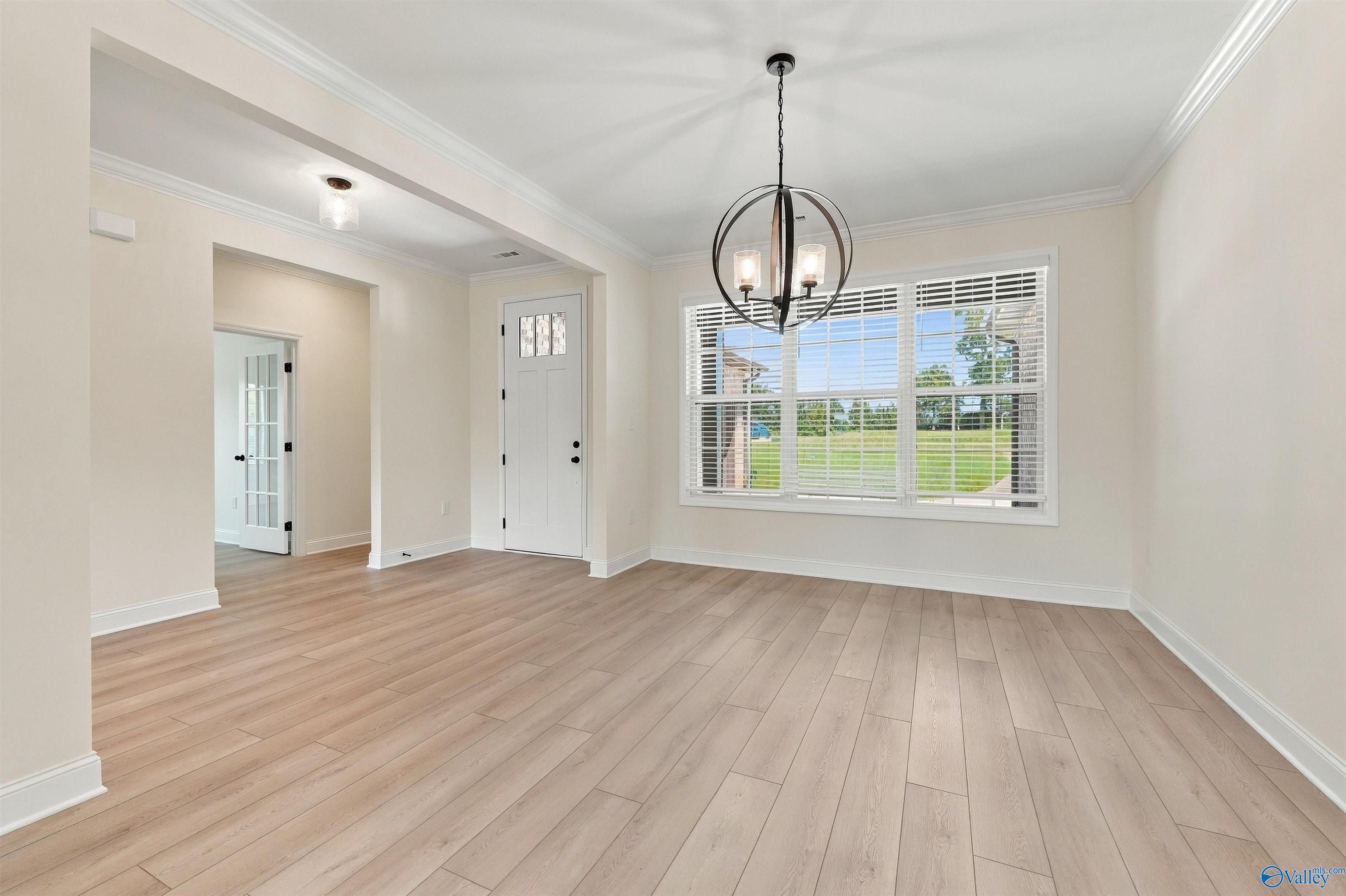 Bright dining room with orb chandelier, wood-look tile flooring, and garden window in Davidson Homes' The Valencia, Huntsville, AL