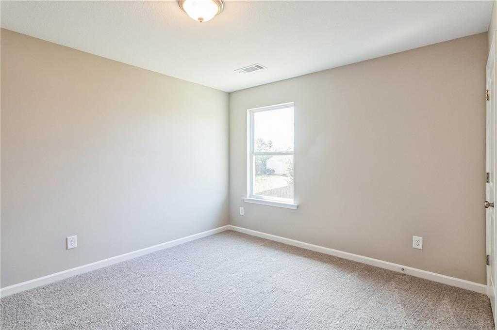 Bright secondary bedroom featuring beige walls, neutral carpet, large window, and ceiling light in Evermore Homes The Stella, Perry, Georgia