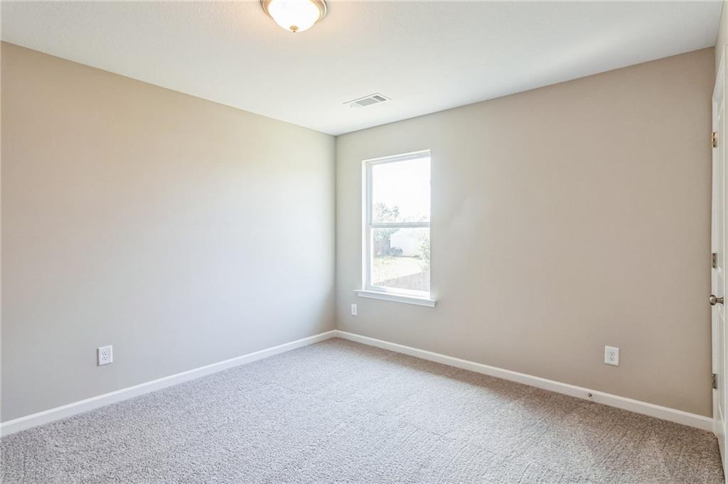 Bright secondary bedroom featuring beige walls, neutral carpet, large window, and ceiling light in Evermore Homes The Stella, Perry, Georgia