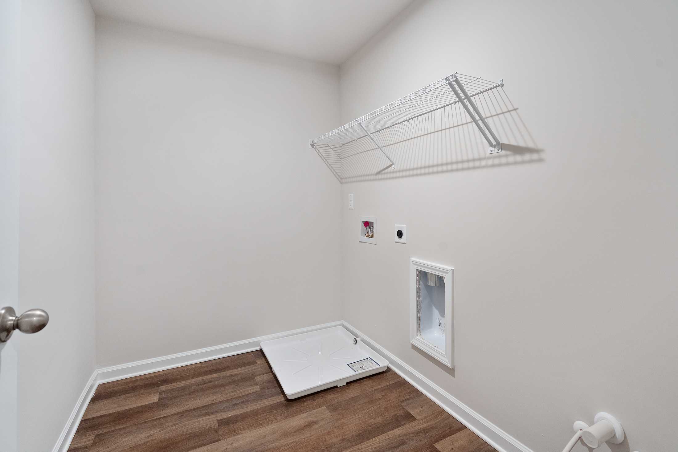 Laundry room in The Cary B Davidson Homes design featuring wire shelving, washer dryer hookups, utility sink, and hardwood floors
