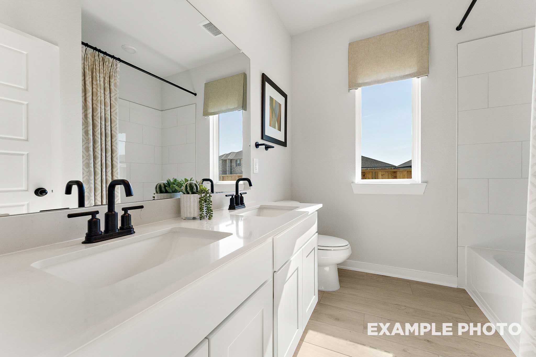 Modern bathroom with double vanity, quartz countertops, and matte black fixtures in The Everett E, Sundance Cove, Crosby.