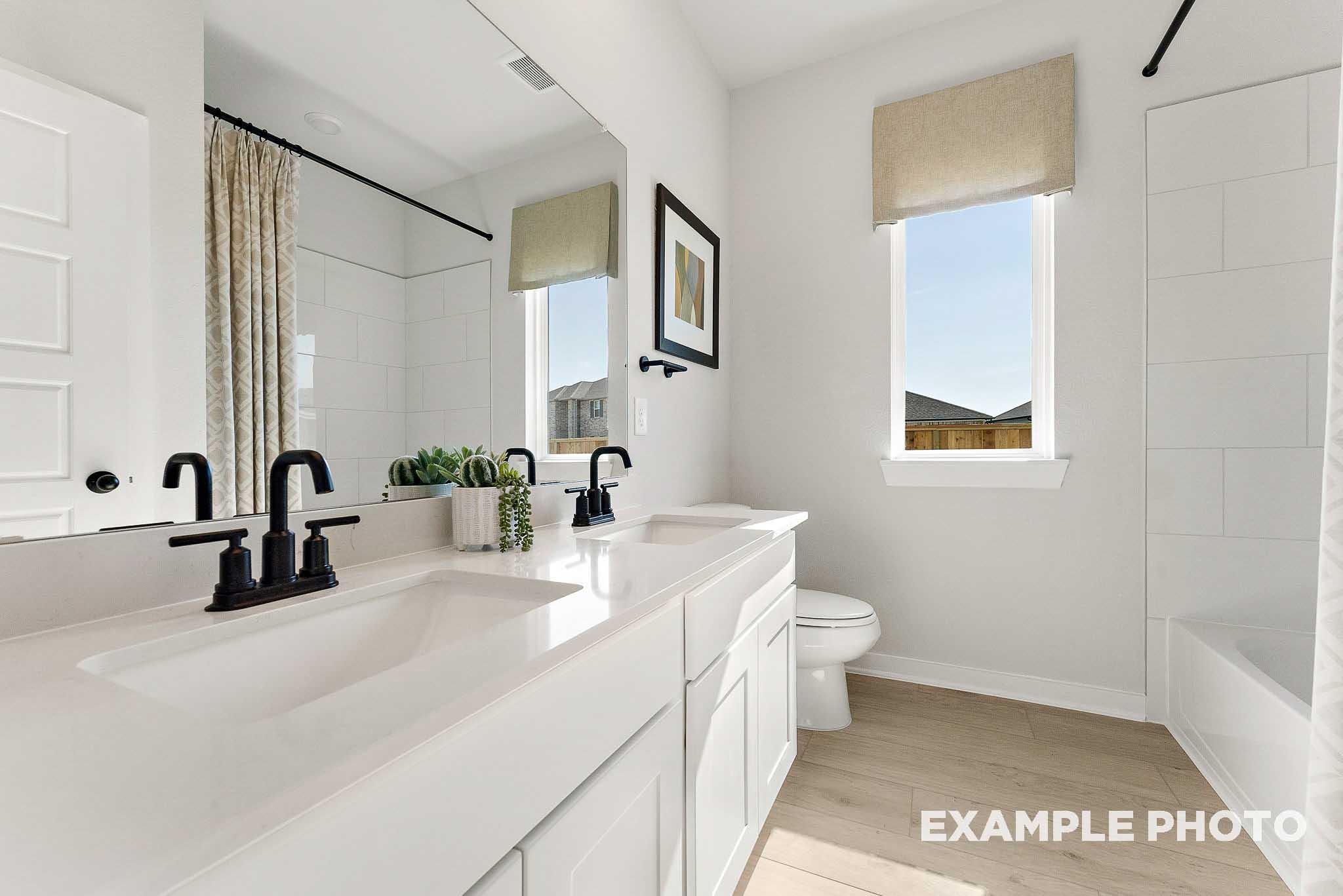 Modern bathroom with double vanity, quartz countertops, and matte black fixtures in The Everett E, Sundance Cove, Crosby.