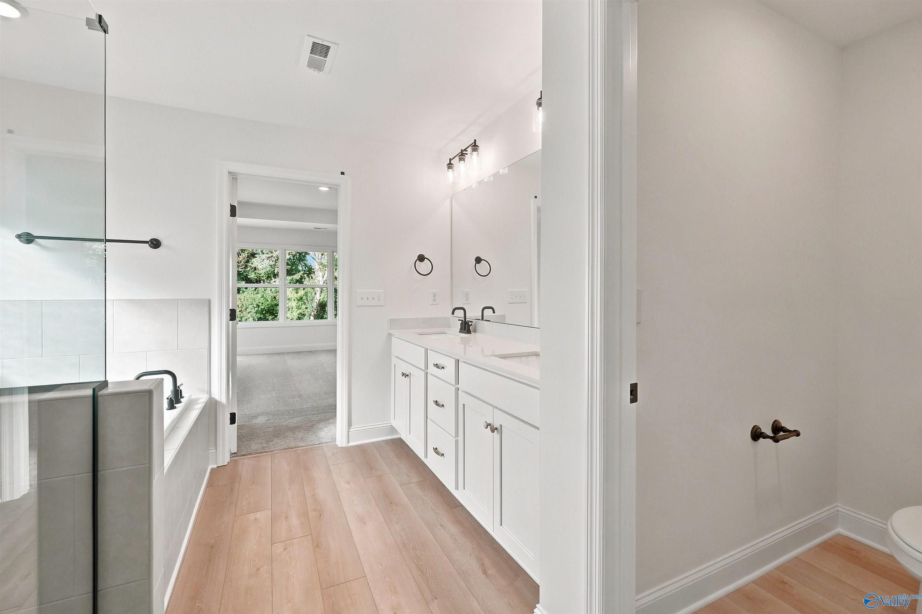 Modern master bathroom with dual vanity and glass-enclosed tub in The Chelsea C floor plan at Creek Grove, New Market, AL.