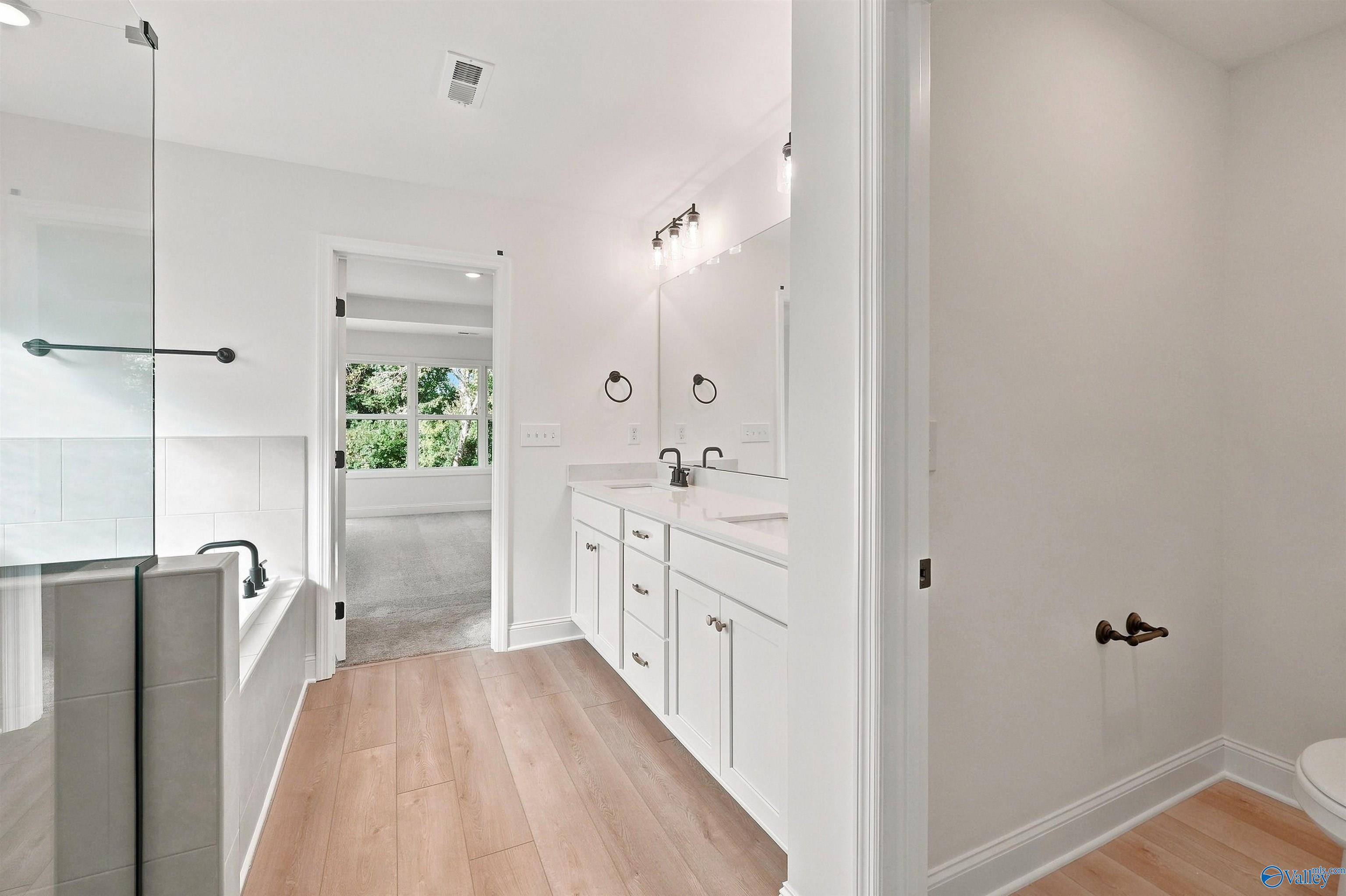 Modern master bathroom with dual vanity and glass-enclosed tub in The Chelsea C floor plan at Creek Grove, New Market, AL.