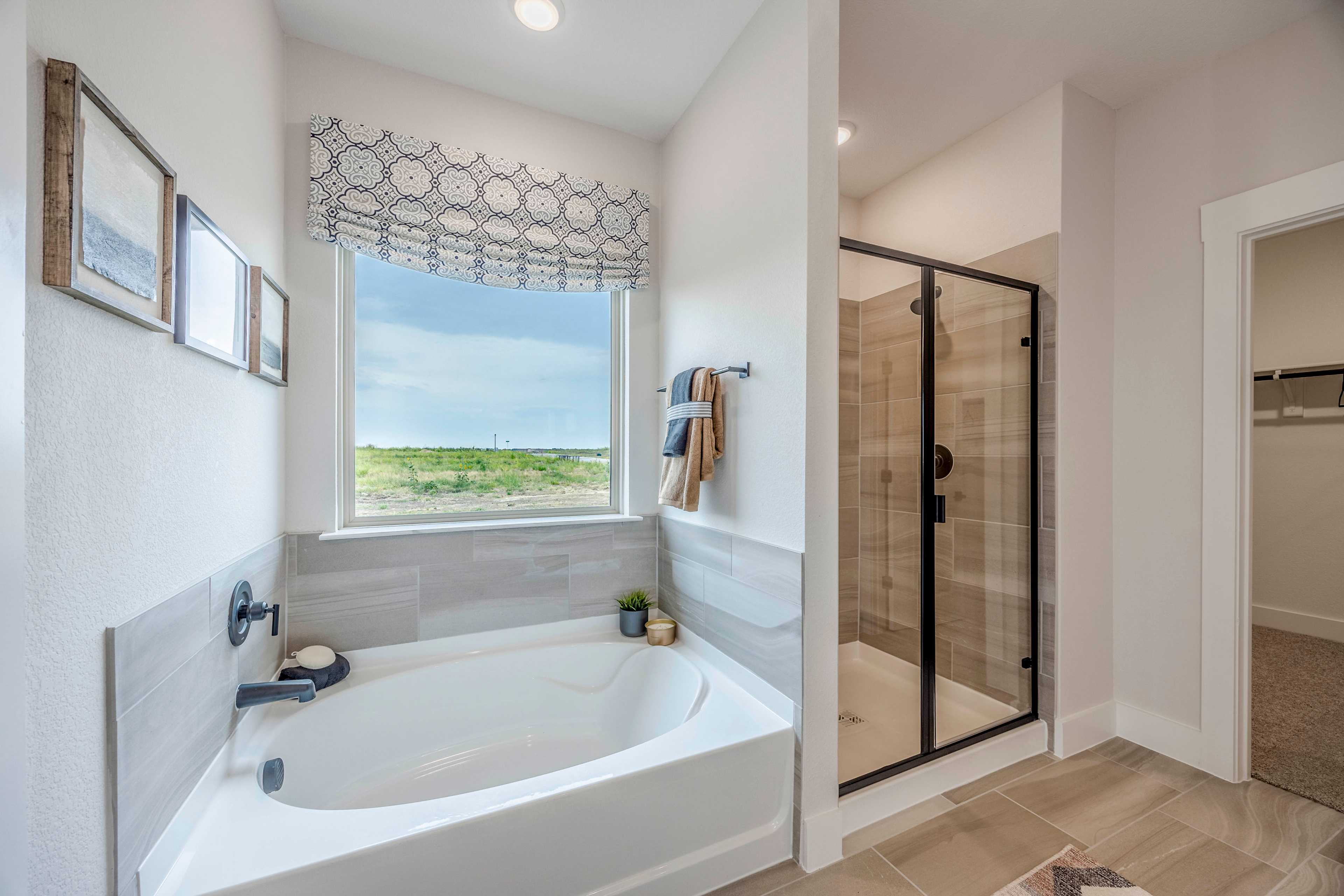 Spacious master bathroom in The Rockford with freestanding tub, frameless glass shower, and scenic window view