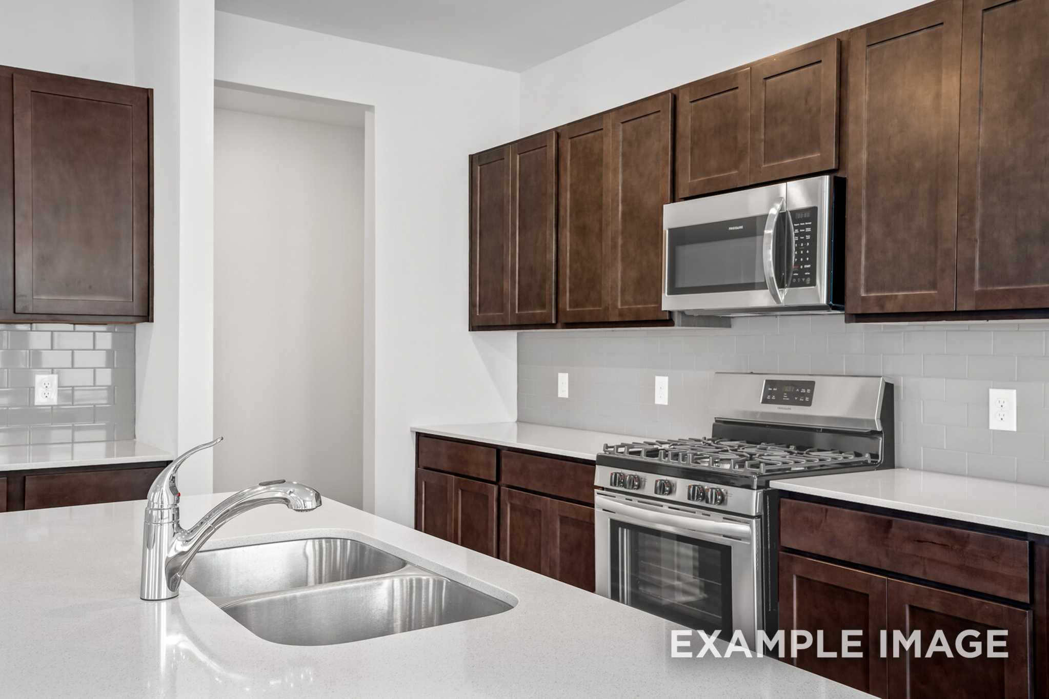 Modern Grayson C kitchen with dark shaker cabinets, stainless steel appliances, white quartz counters, and subway tile backsplash