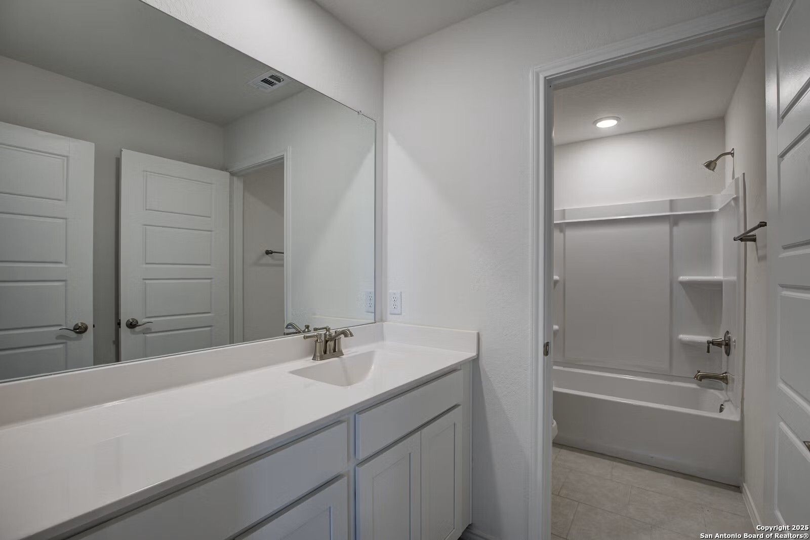 Modern double vanity bathroom with large mirror, tub-shower combo in Davidson Homes The Douglas B, Seguin, Texas