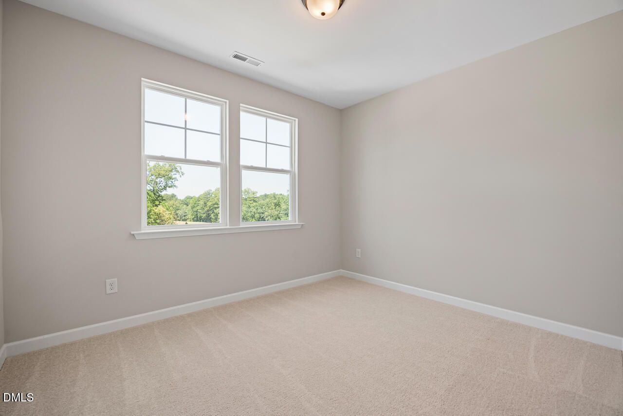 Bright, carpeted bedroom with neutral walls and large windows in The Chestnut floor plan by Davidson Homes in Aberdeen, NC.
