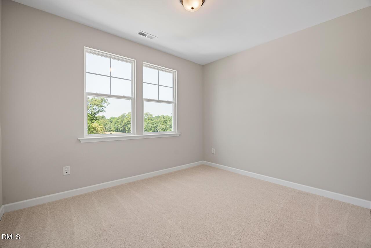 Bright, carpeted bedroom with neutral walls and large windows in The Chestnut floor plan by Davidson Homes in Aberdeen, NC.