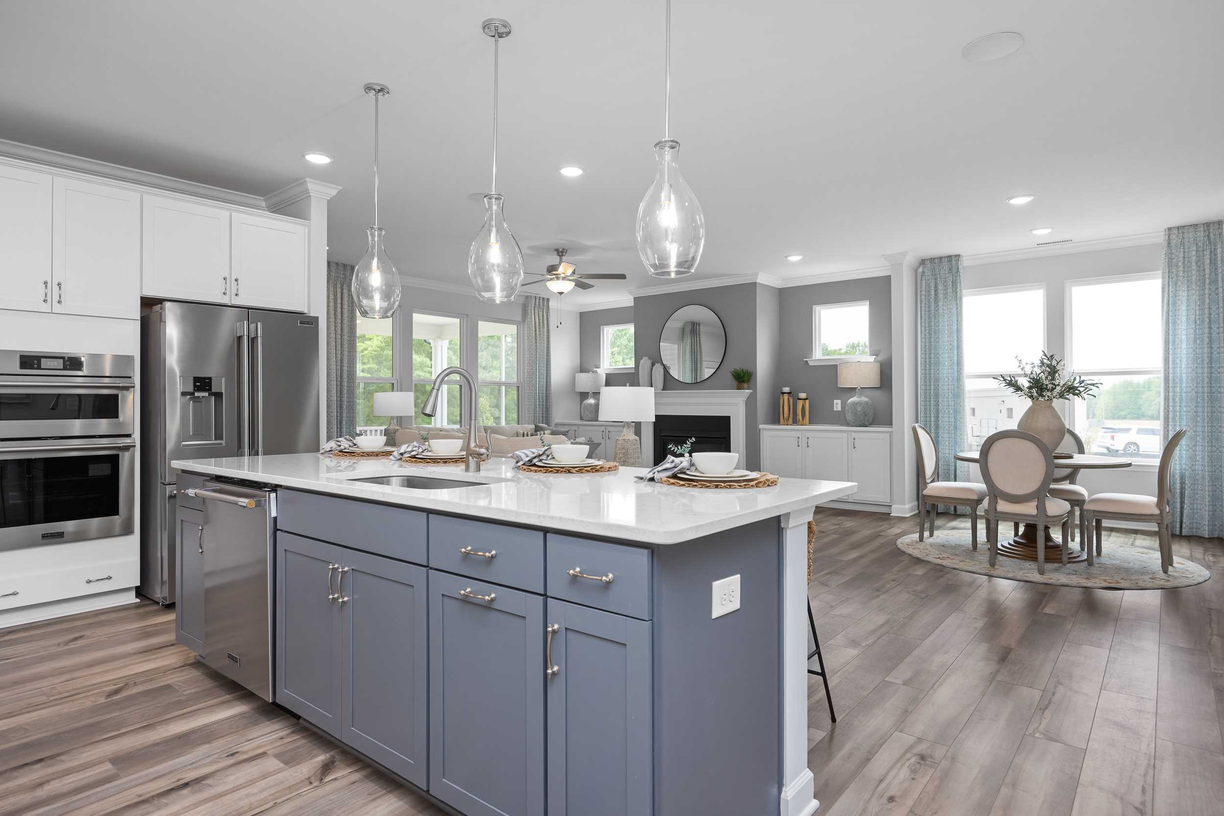 Modern kitchen with quartz island, stainless appliances, white cabinets, and hardwood floors at Tobacco Road in Angier, NC