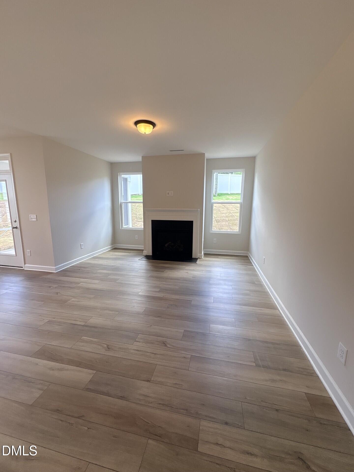 Spacious living room with fireplace and wood-look flooring in The Ash C floor plan at Woodland Crossing, Zebulon, NC.