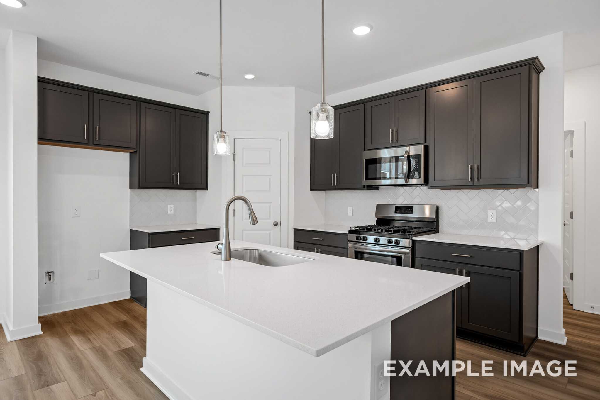 Spacious kitchen in The Murray B featuring espresso cabinets, white quartz island, stainless appliances, and pendant lights