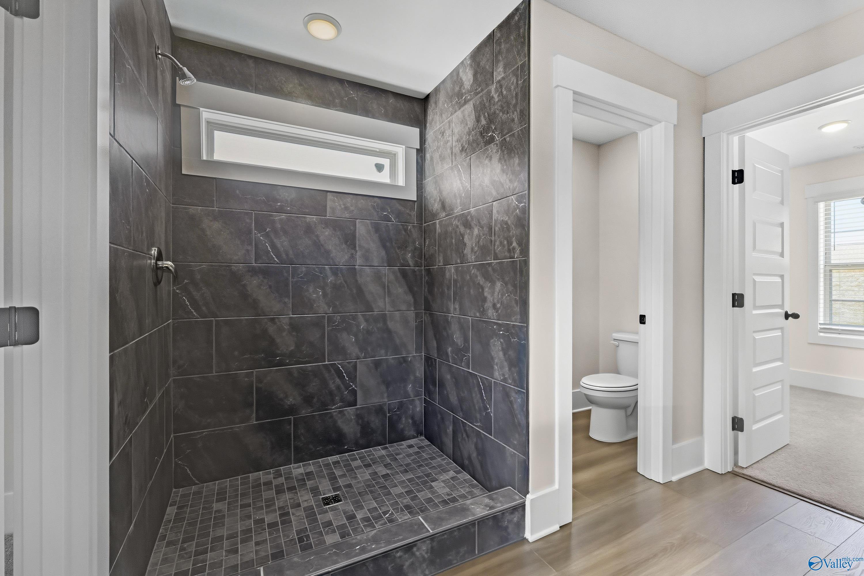 Modern walk-in shower with slate gray tiles and frameless glass door in master bathroom, The Shelby A by Davidson Homes, Athens AL