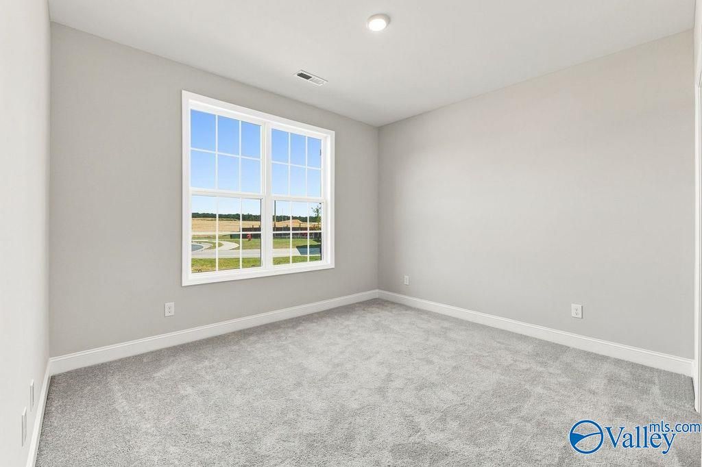 Bright bedroom with gray carpet and large window in Davidson Homes The Rockford floor plan, Cain Park, Hartselle, Alabama