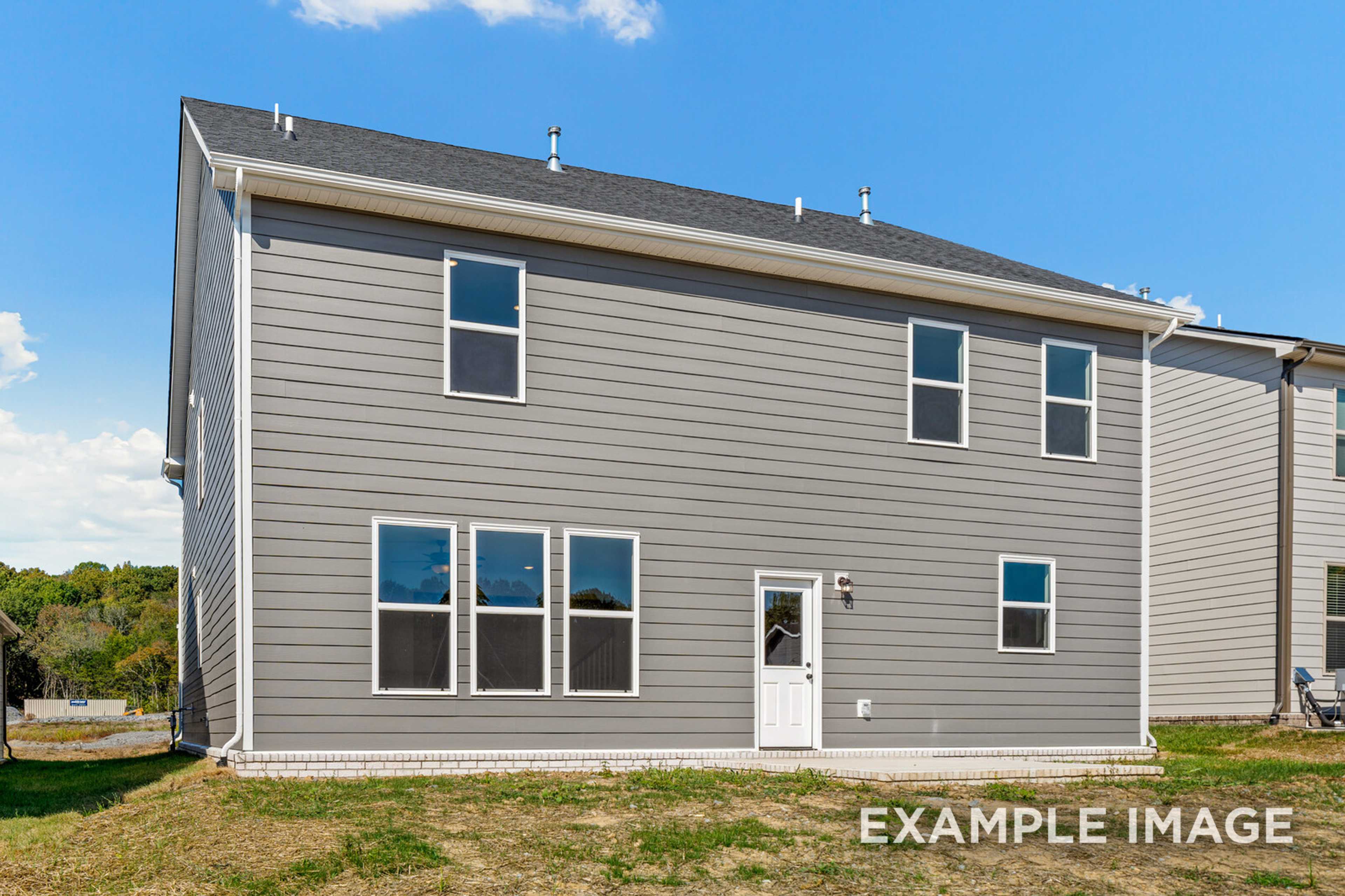 Rear elevation of The Henry C two-story home featuring gray siding, multiple windows, white back door, and grassy yard in Mt. Juliet