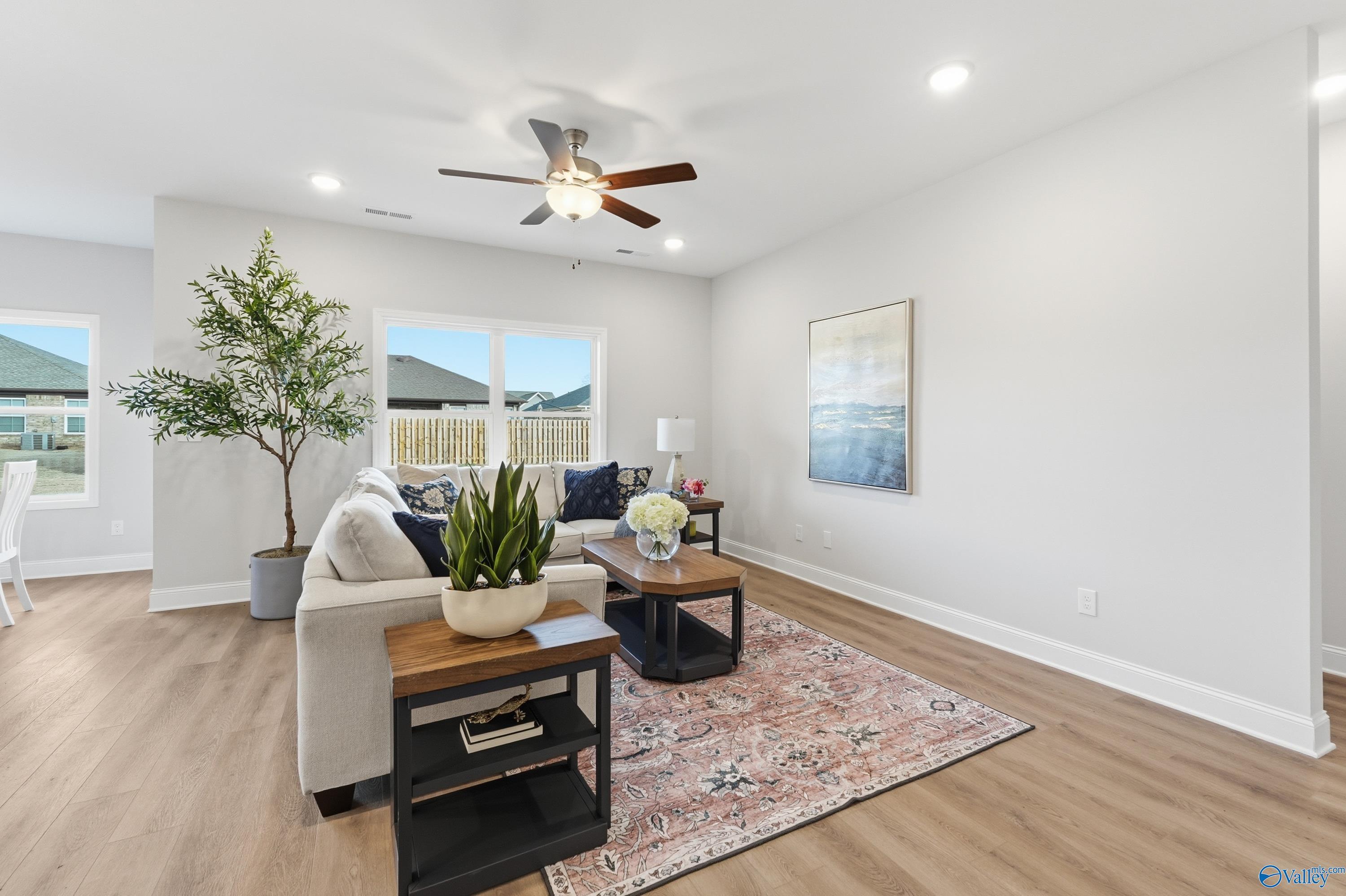 Cozy living room with beige sofa, wooden coffee tables, potted tree, and large windows in The Asheville 3-bedroom home, Toney, Alabama