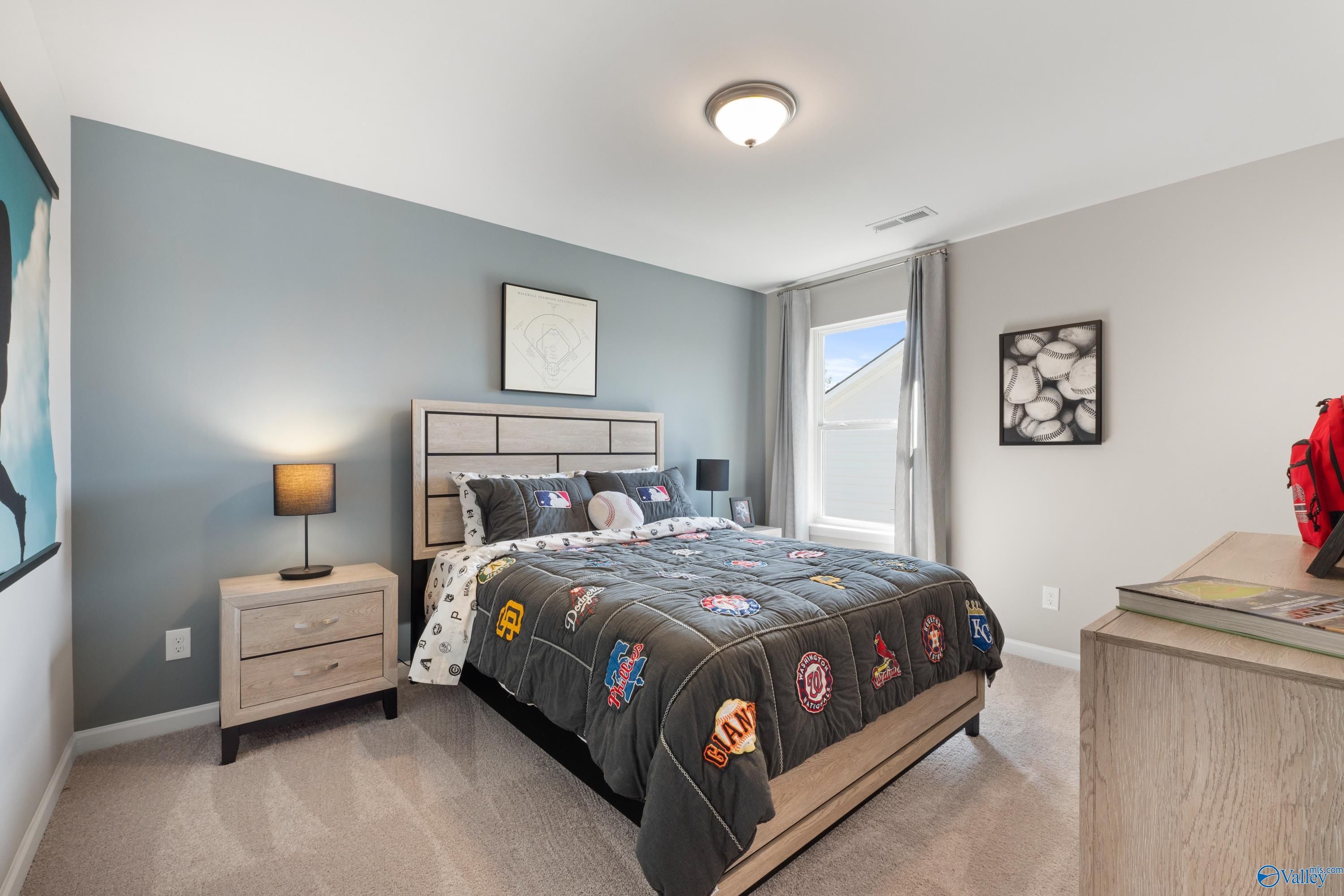 Cozy boy's bedroom with MLB team quilt, baseball artwork, and wood furniture in Davidson Homes The Stella, Madison, Alabama