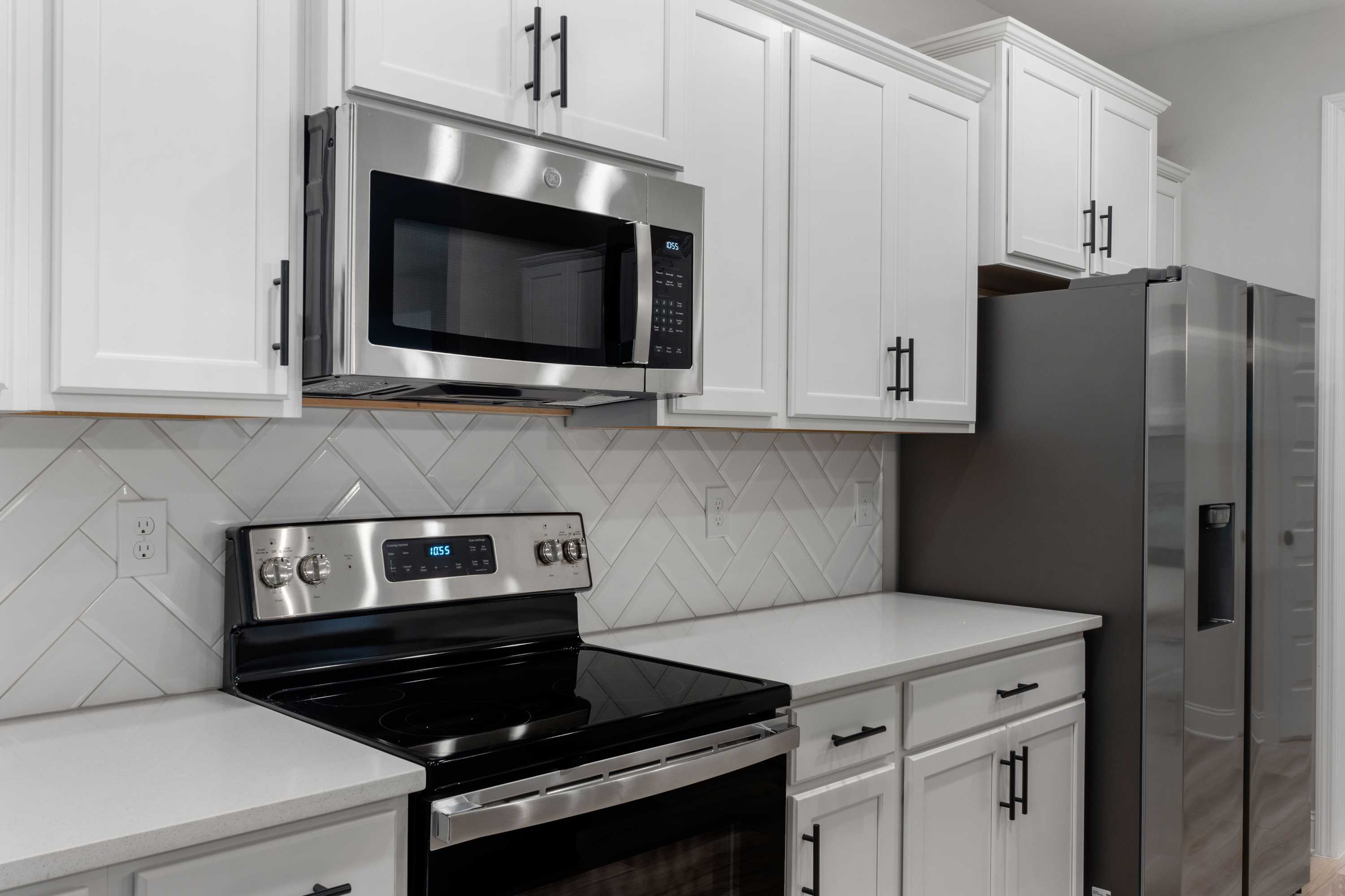 Spacious kitchen in The Oxford by Davidson Homes featuring white shaker cabinets, stainless steel appliances, and subway tile backsplash