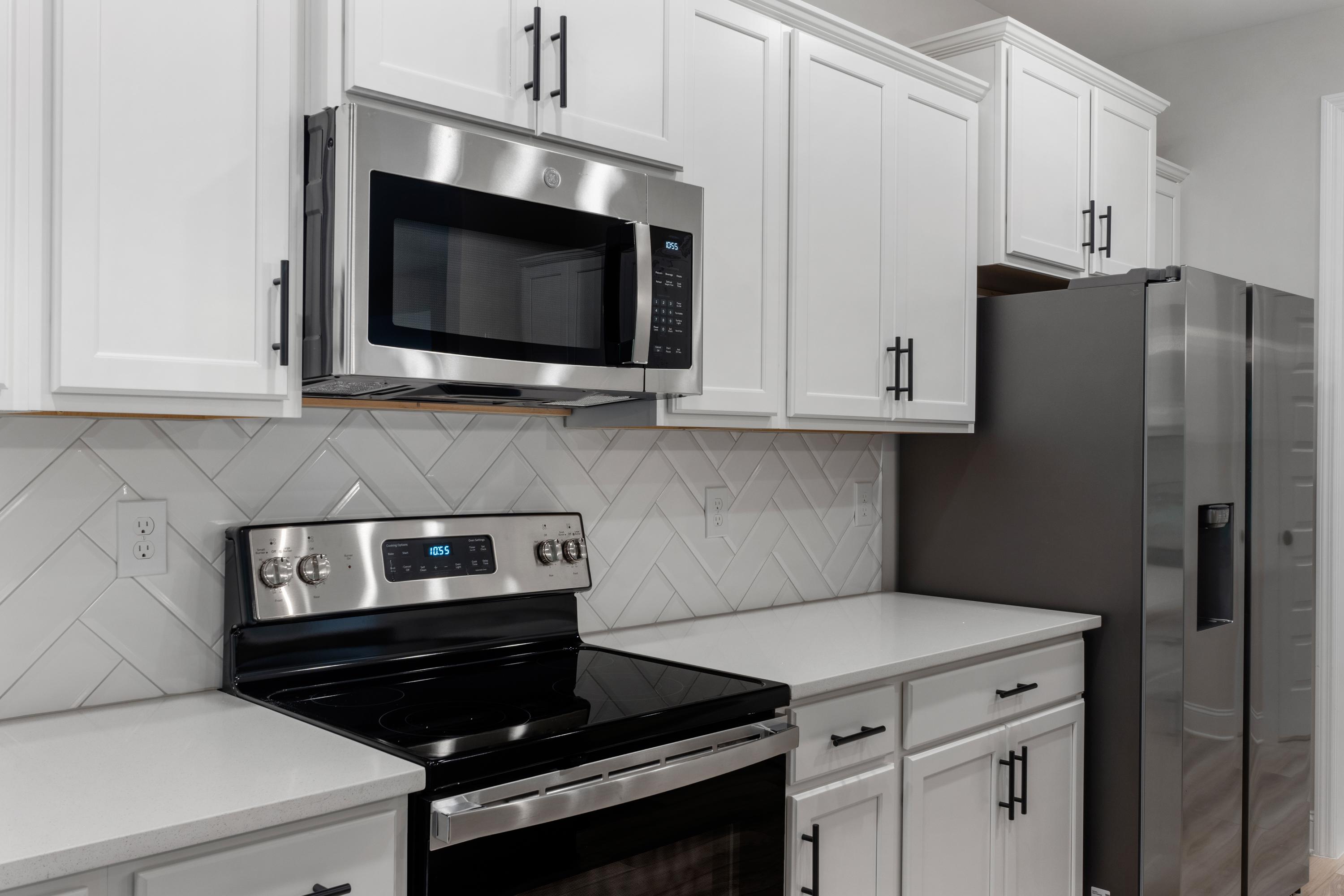 Spacious kitchen in The Oxford by Davidson Homes featuring white shaker cabinets, stainless steel appliances, and subway tile backsplash