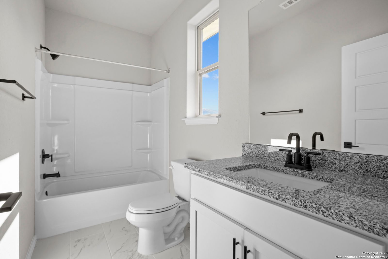 Modern guest bathroom with granite countertop vanity, tub-shower combo, and neutral finishes in Davidson Homes The Daphne H, Seguin, Texas