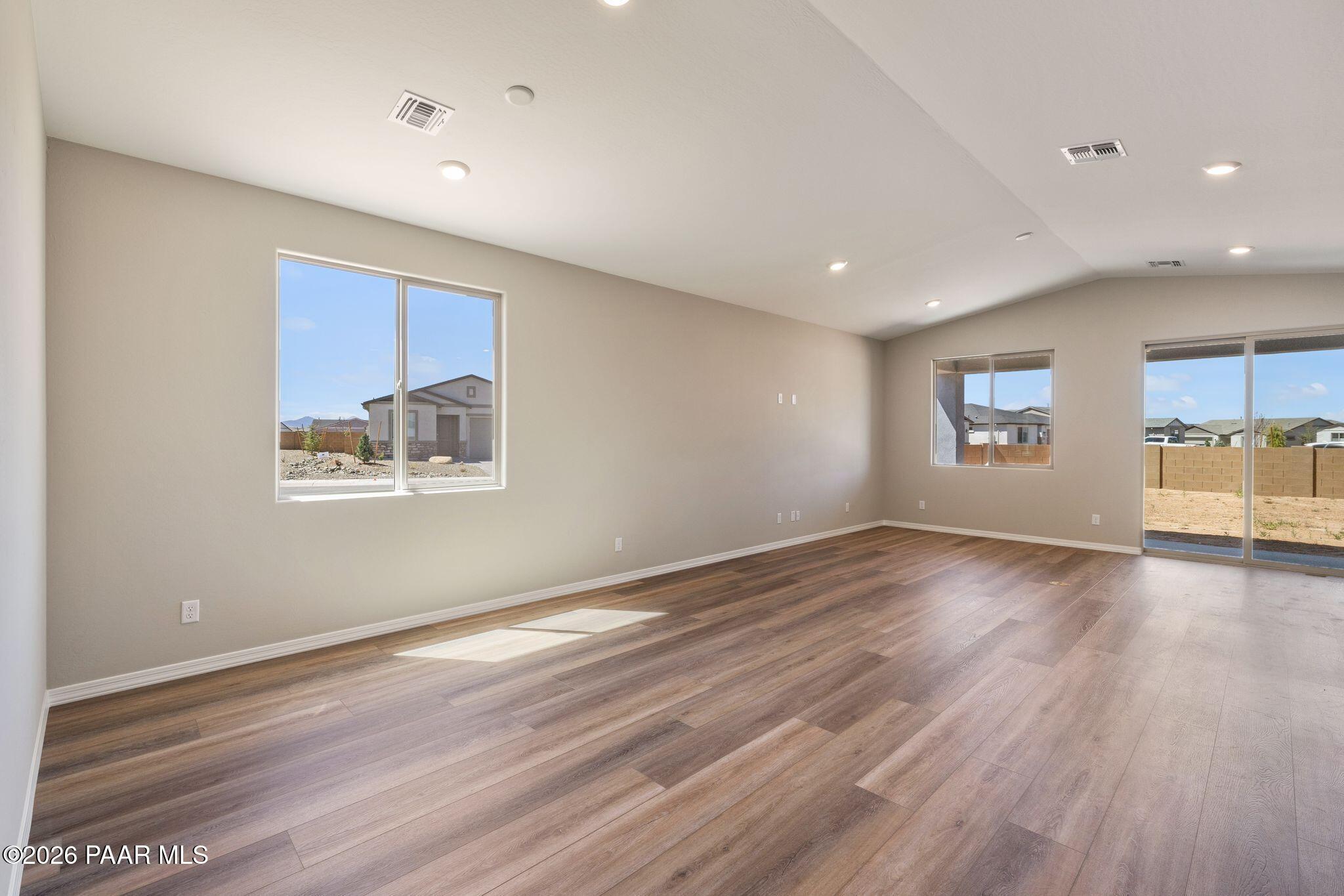 Spacious living room with beige walls, wood laminate floors, and sliding doors to desert patio in Davidson Homes The Frontier A, Prescott Valley, Arizona
