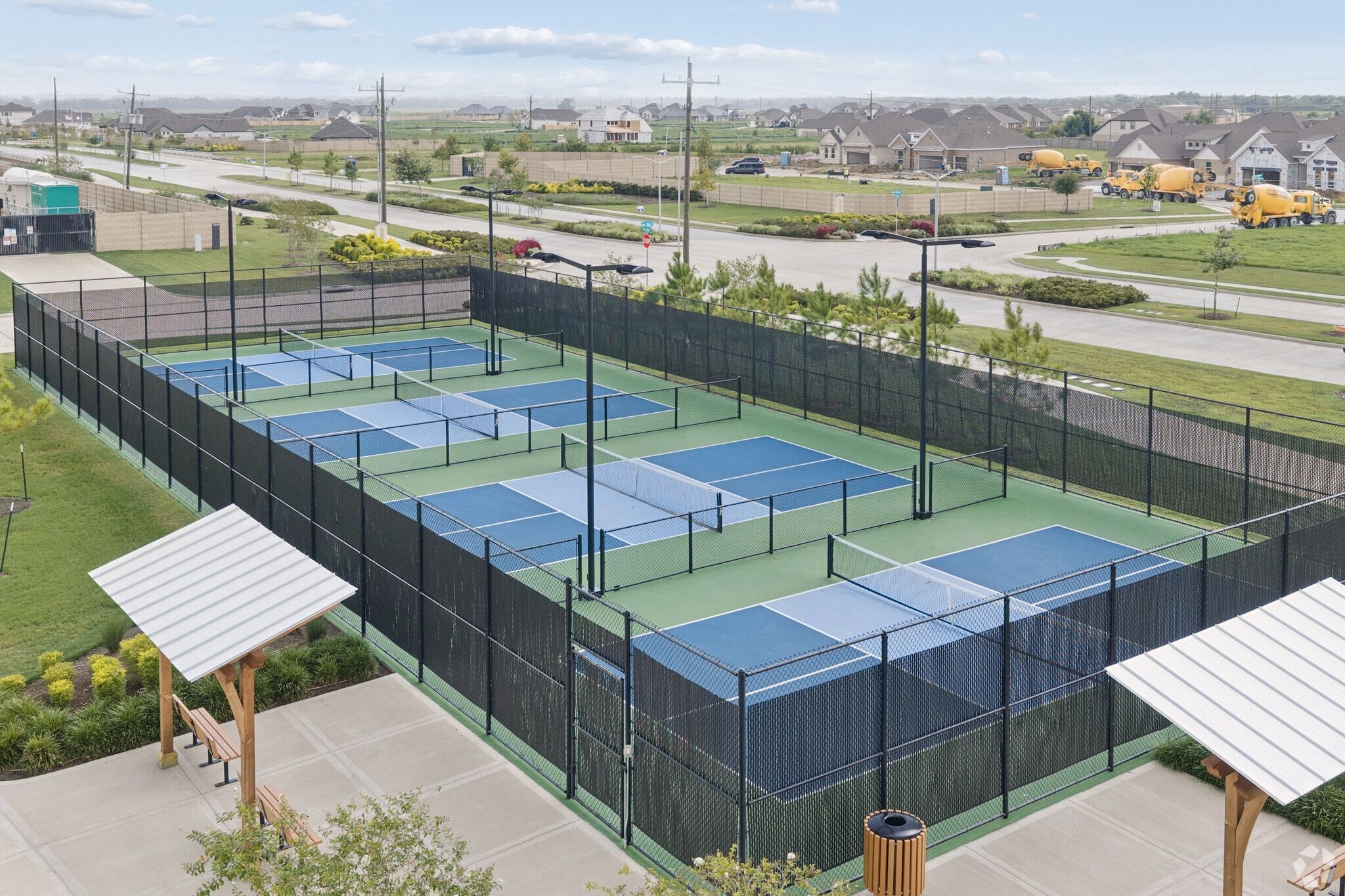 Pickleball courts at River Ranch Meadows in Dayton, Texas with shaded seating and new homes by Davidson Homes in background