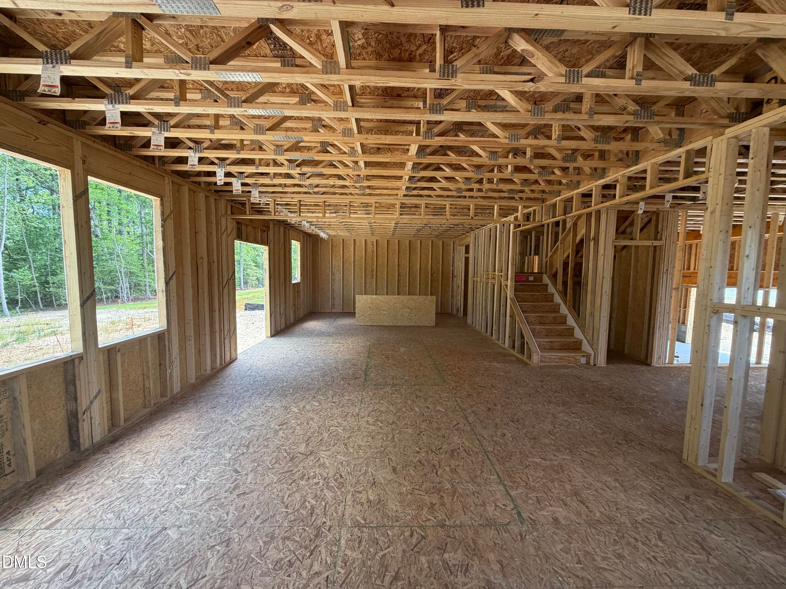 Spacious framed interior with wooden beams, staircase, and large windows overlooking woods in The Hickory II C, Lillington, NC