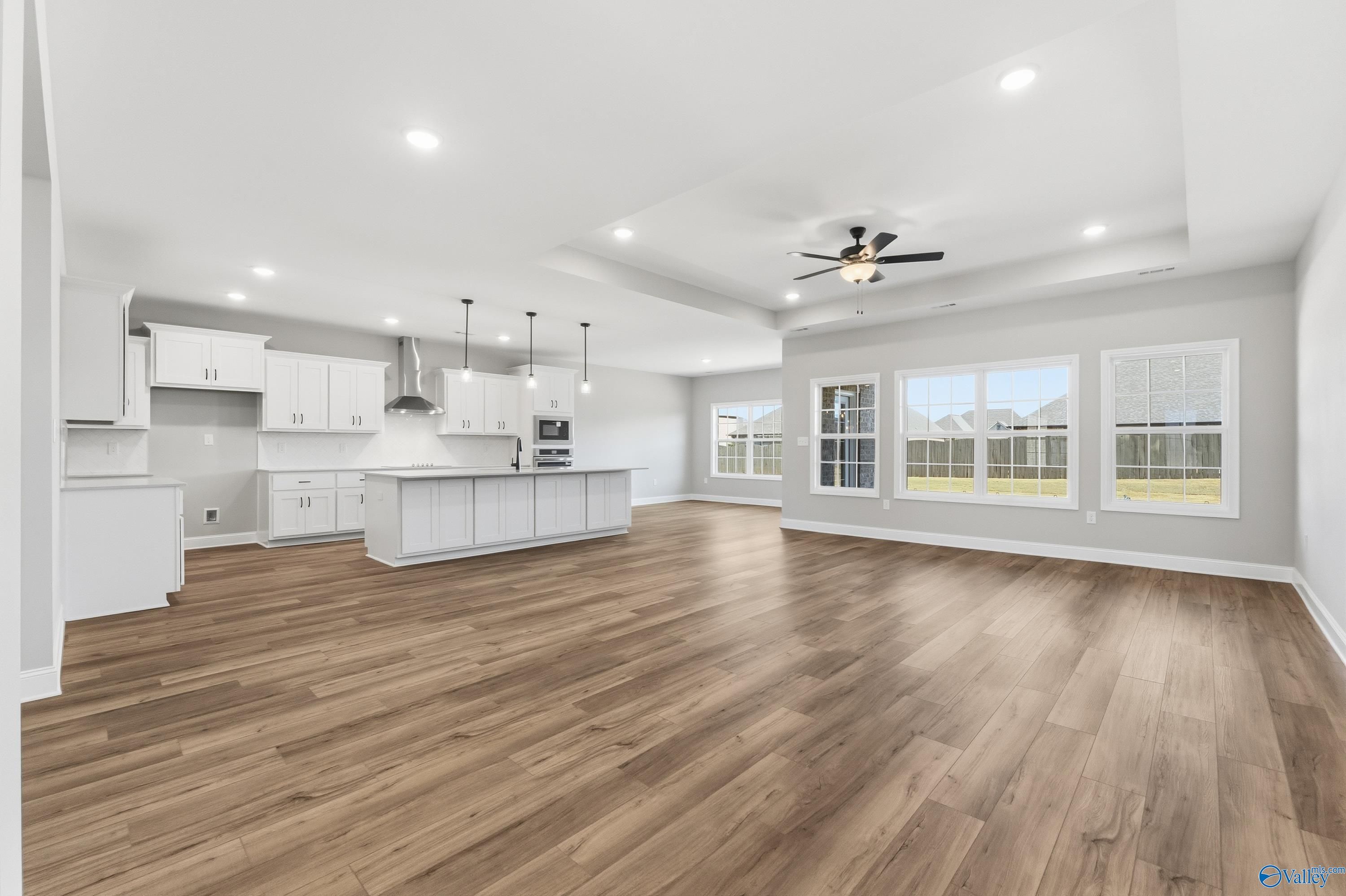 Bright open-concept kitchen with white cabinets, large island, hardwood floors, and large windows in The Finleigh, Meridianville, Alabama
