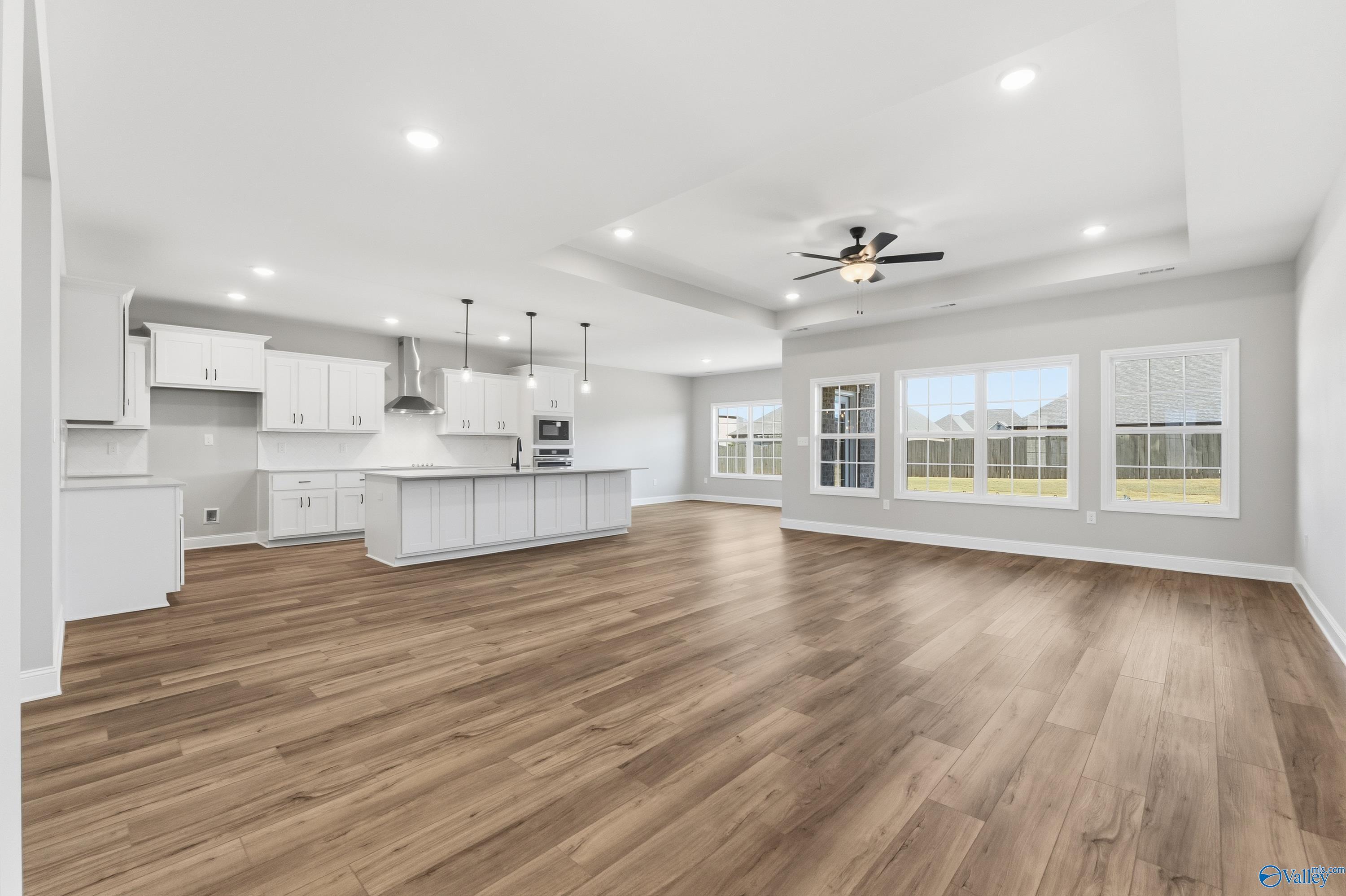 Bright open-concept kitchen with white cabinets, large island, hardwood floors, and large windows in The Finleigh, Meridianville, Alabama