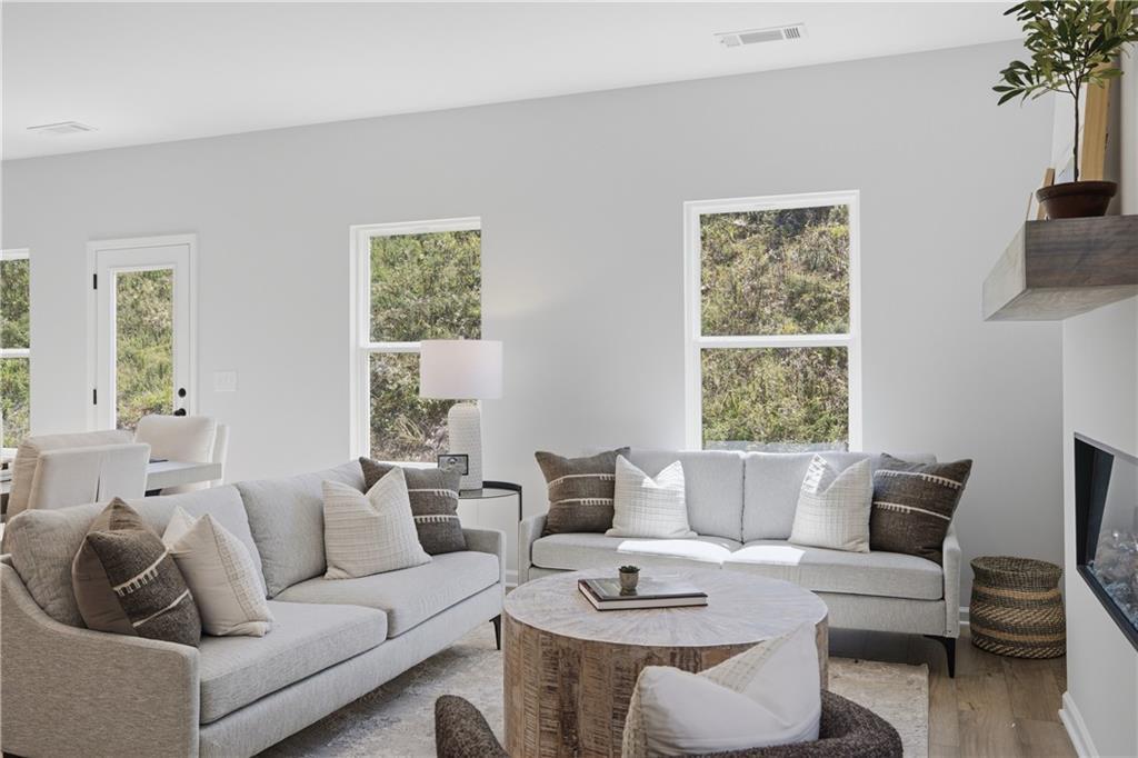 Bright living room with neutral sofas and rustic wood coffee table in Davidson Homes' Hartwell C floor plan, The Bluffs, Canton, GA.