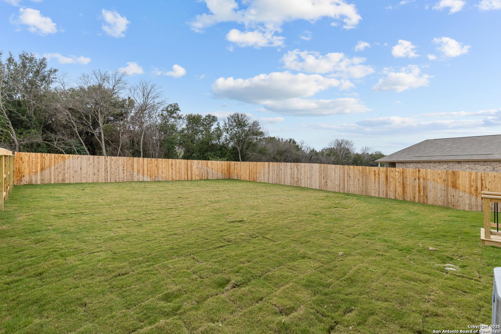 Private backyard with lush green lawn and wooden privacy fence in Davidson Homes The Murray I, Royal Crest, San Antonio