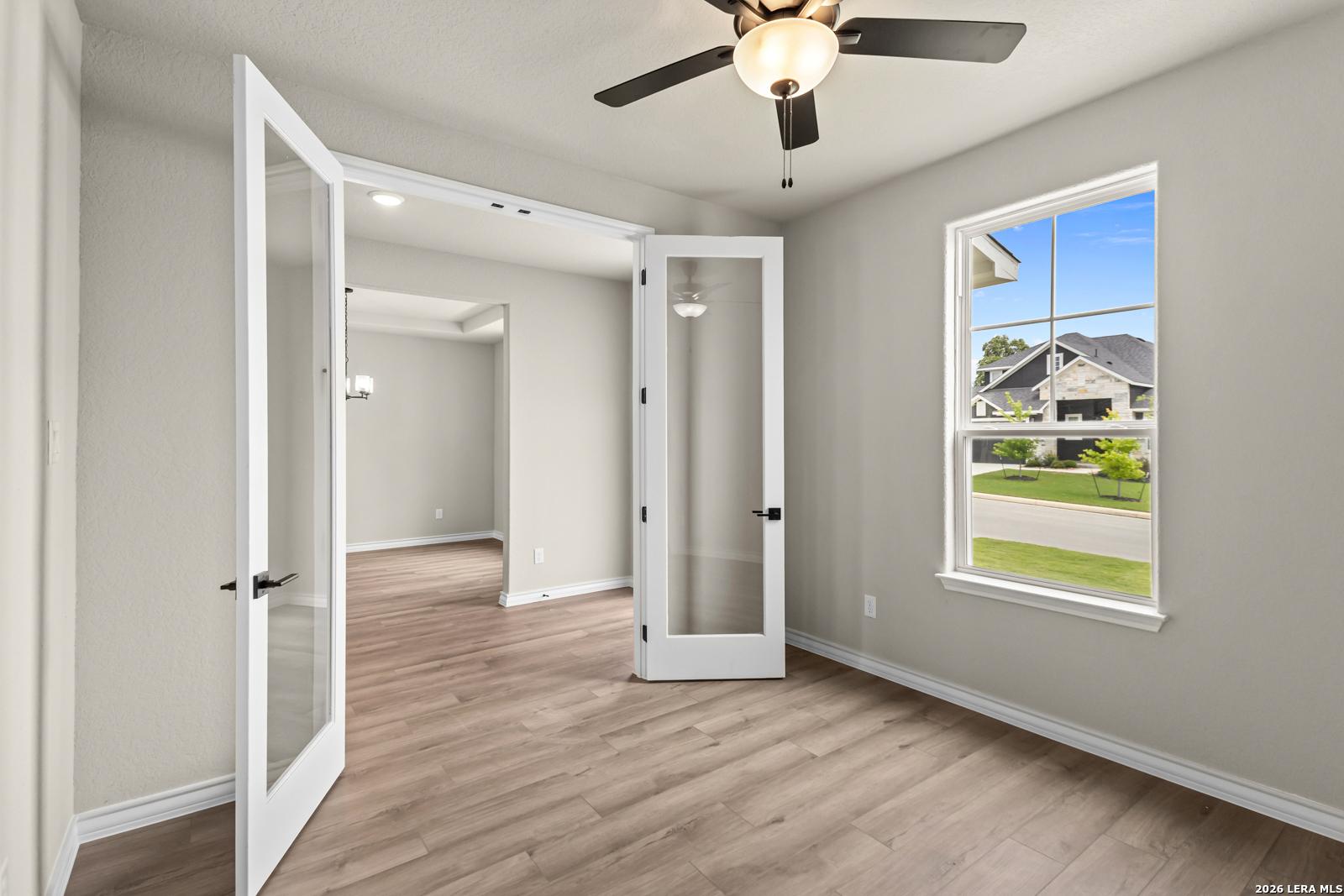 Bright home office with French doors and ceiling fan in The Danbury H floor plan at The Reserve at Potranco Oaks, TX.