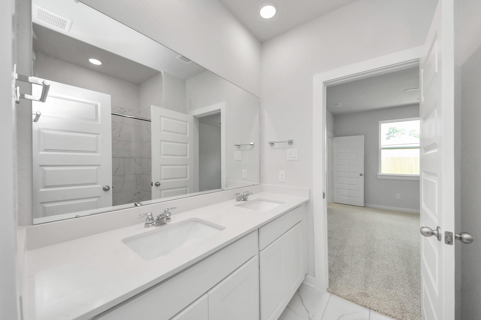 Modern bathroom with double vanity and tiled shower in The Sabine F floor plan at Liberty Estates, Cleveland, Texas.