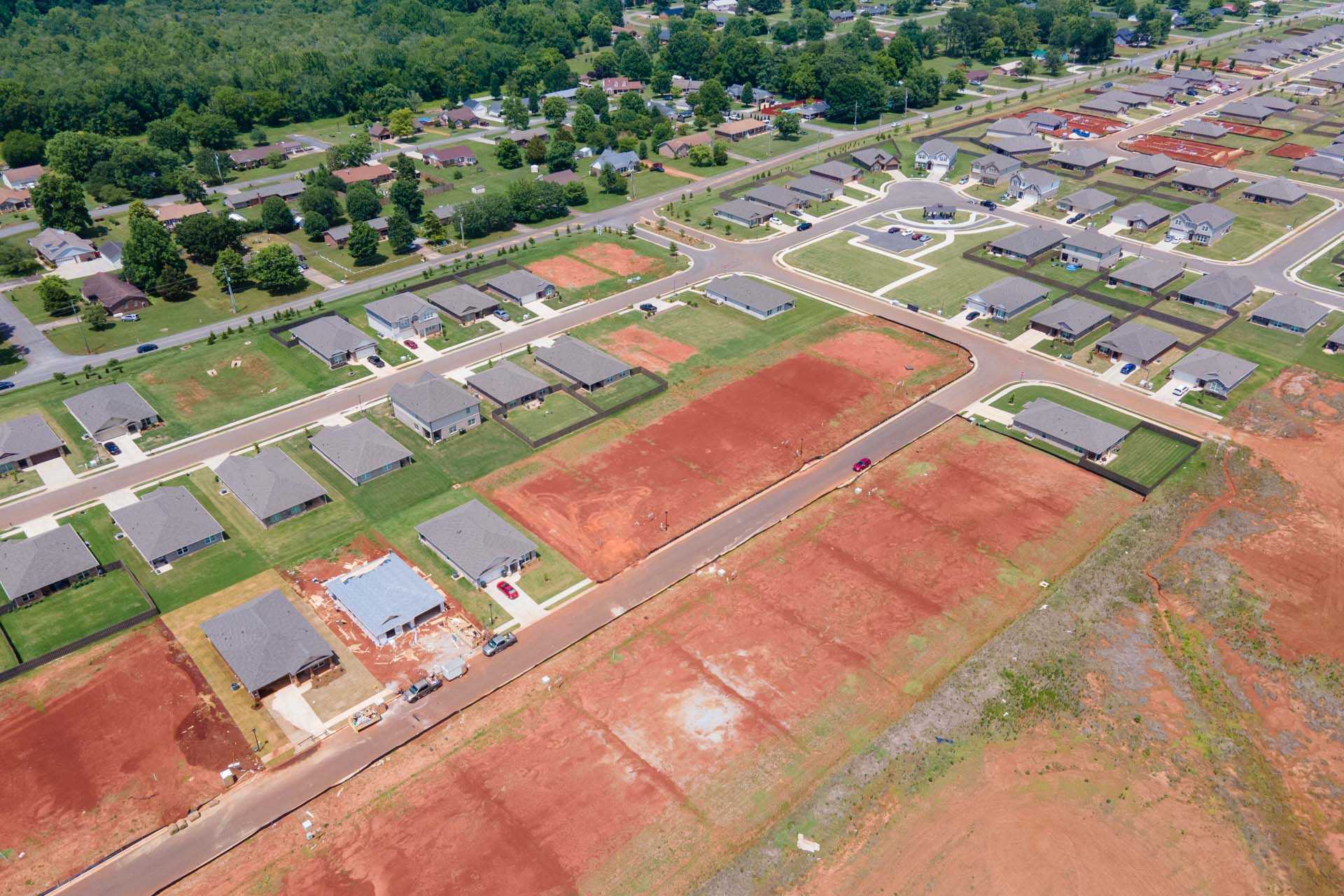 Aerial view of Clearview neighborhood in Hazel Green Alabama with new single-family homes, tree-lined streets, and red clay construction sites by Davidson Homes