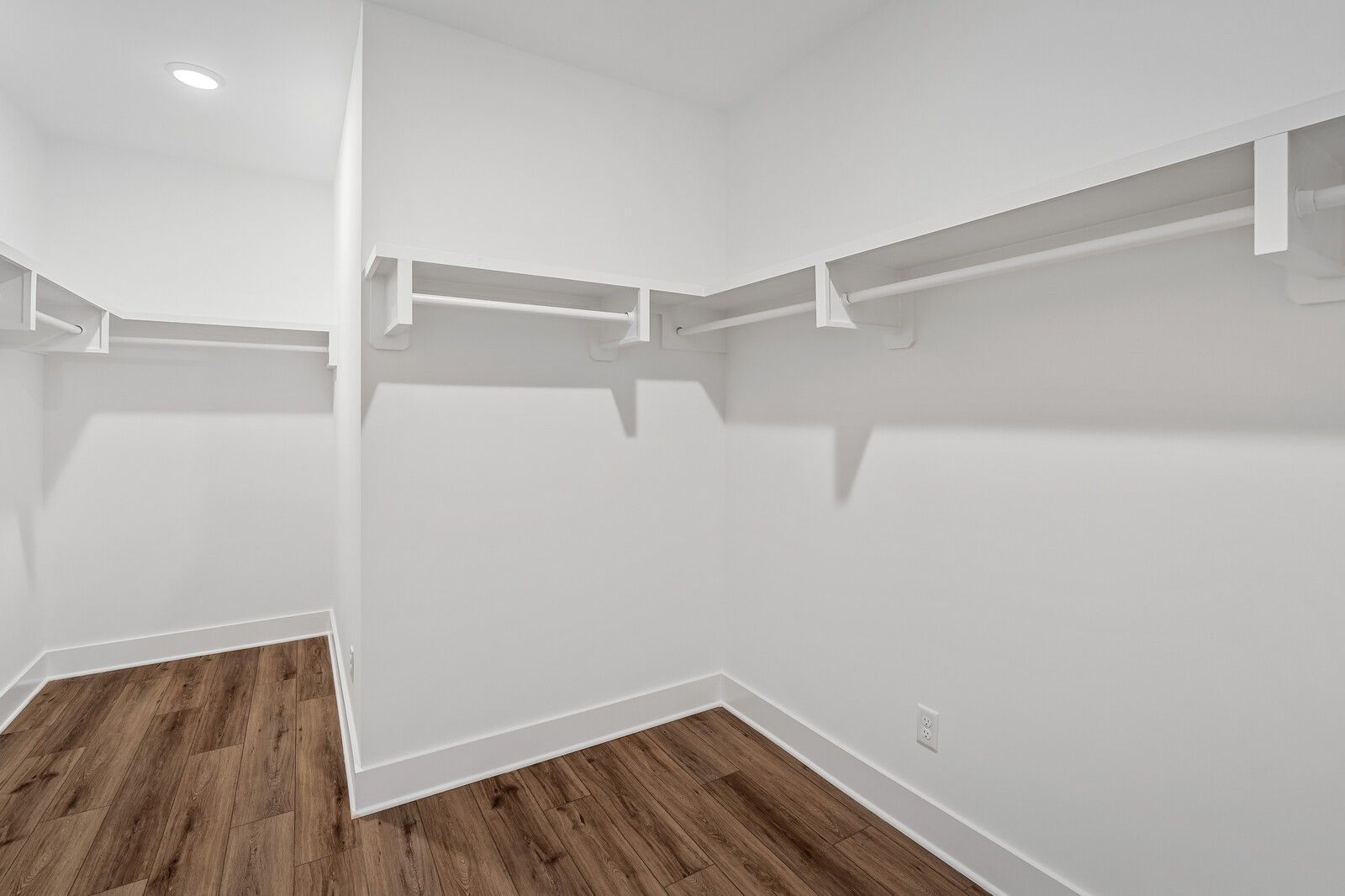 Spacious walk-in closet with white shelving, hanging rods, and hardwood floors in Davidson Homes The Hawkins, Murfreesboro, TN