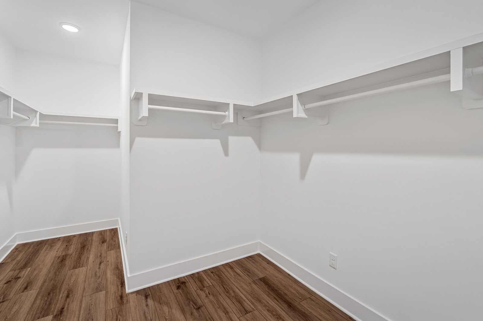 Spacious walk-in closet with white shelving, hanging rods, and hardwood floors in Davidson Homes The Hawkins, Murfreesboro, TN