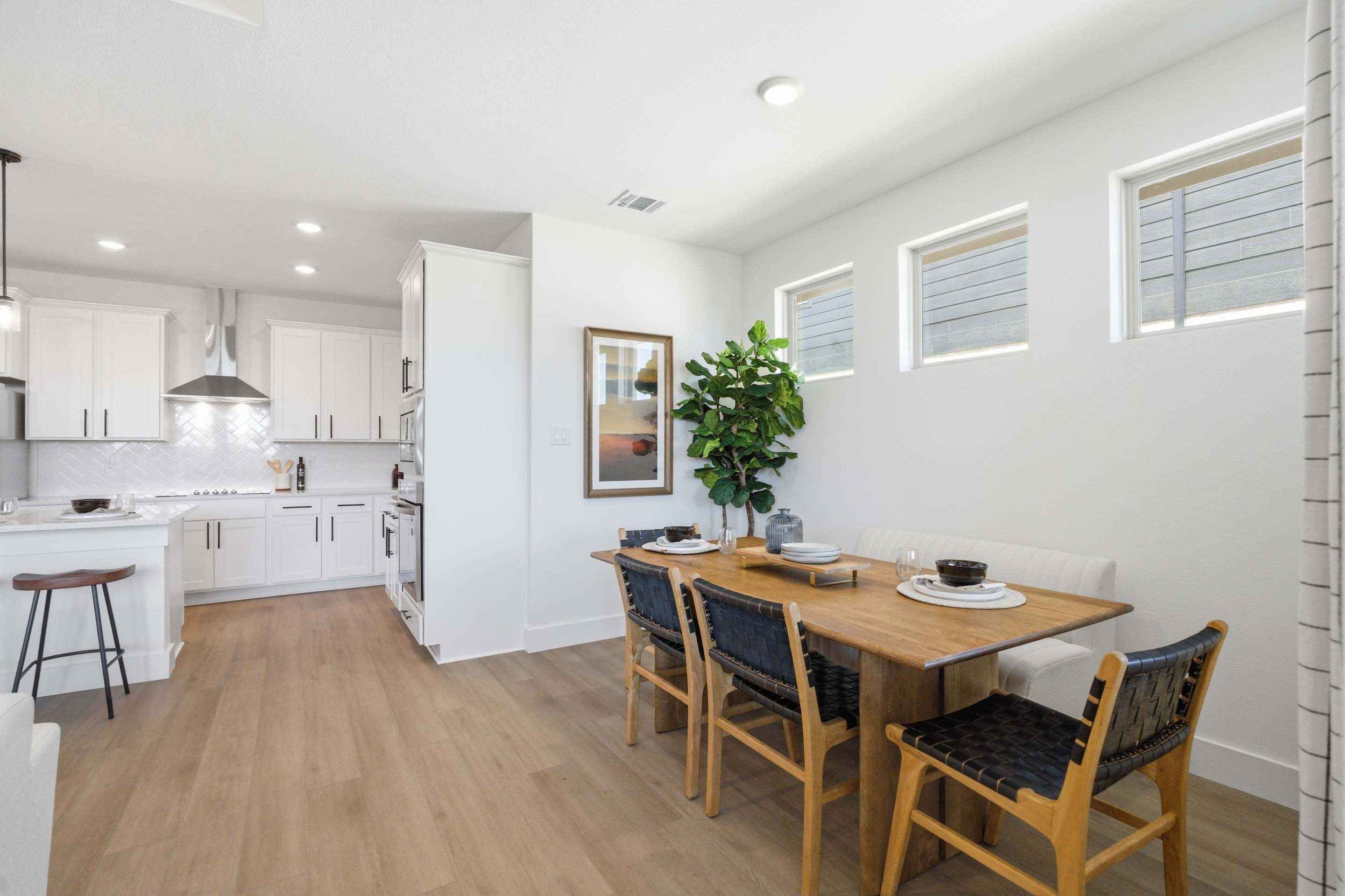 Open-concept kitchen and dining area in The Laurel floor plan featuring white cabinetry, wood dining table, and bar seating.